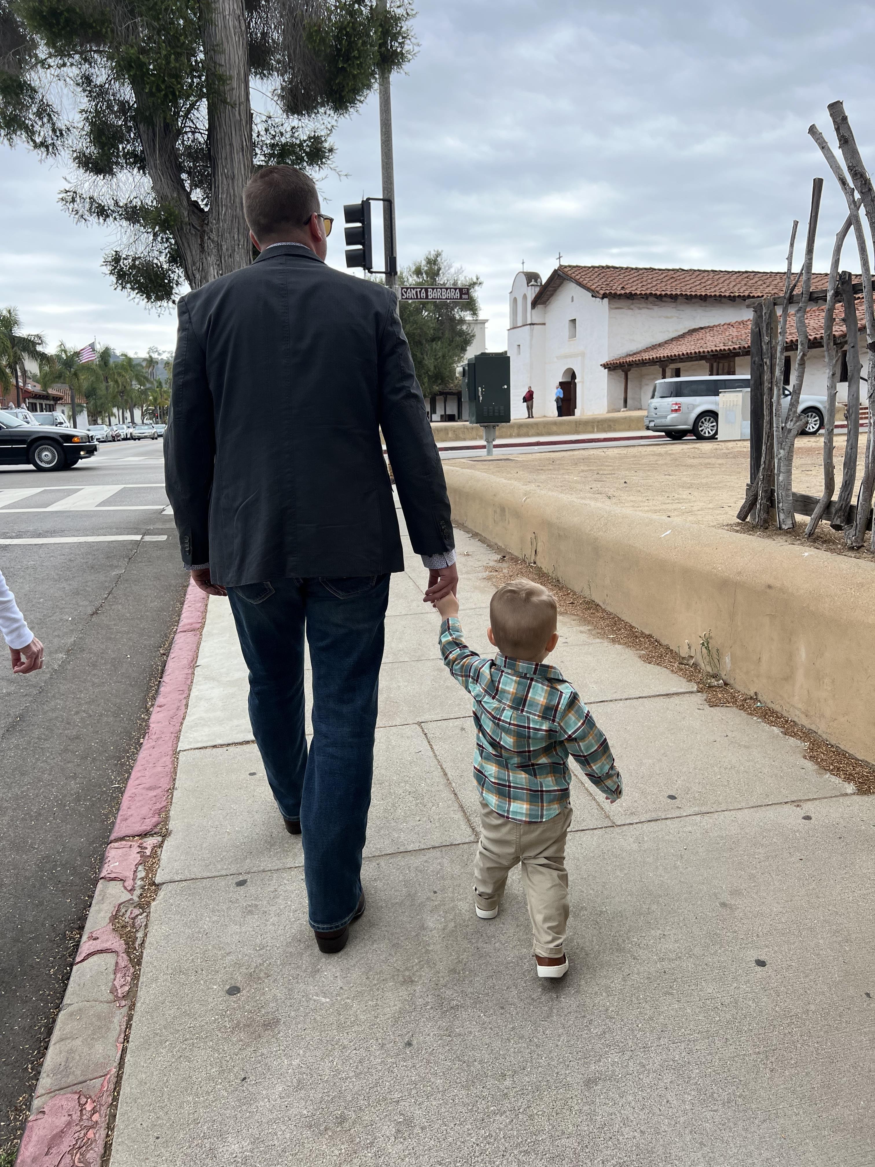 A man and child walking on a sidewalk