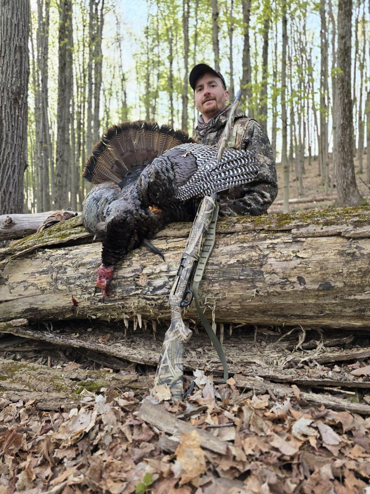A man with a turkey on a log