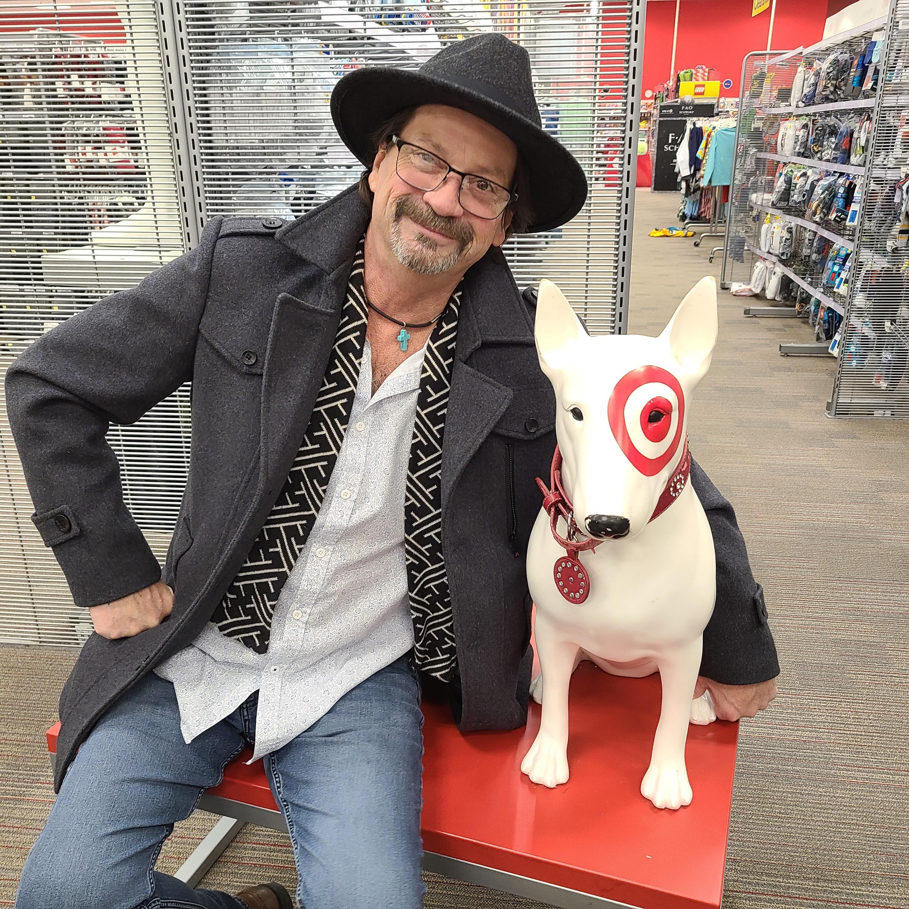 A man sitting on a bench with a dog statue