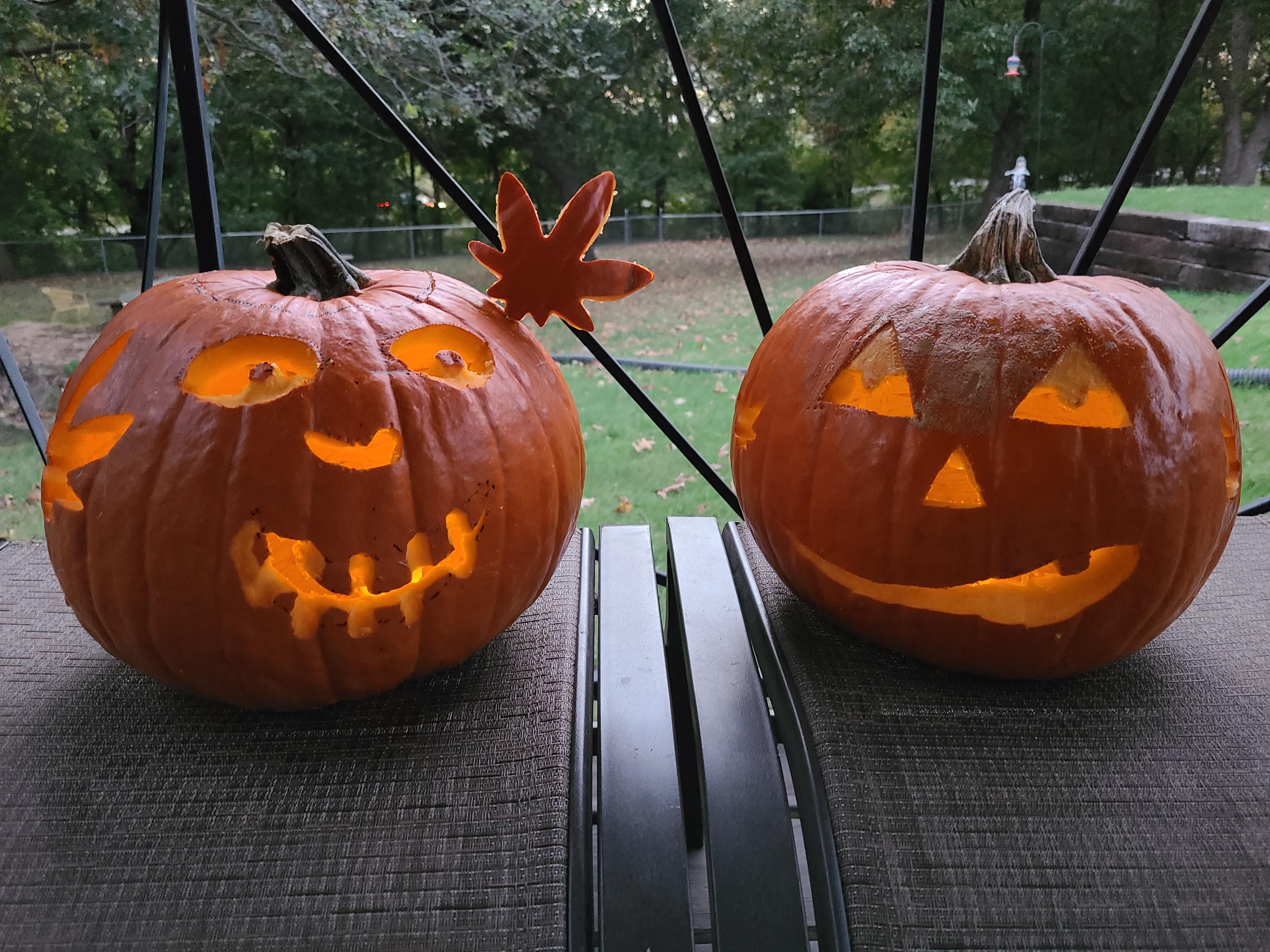 Two carved pumpkins on a bench