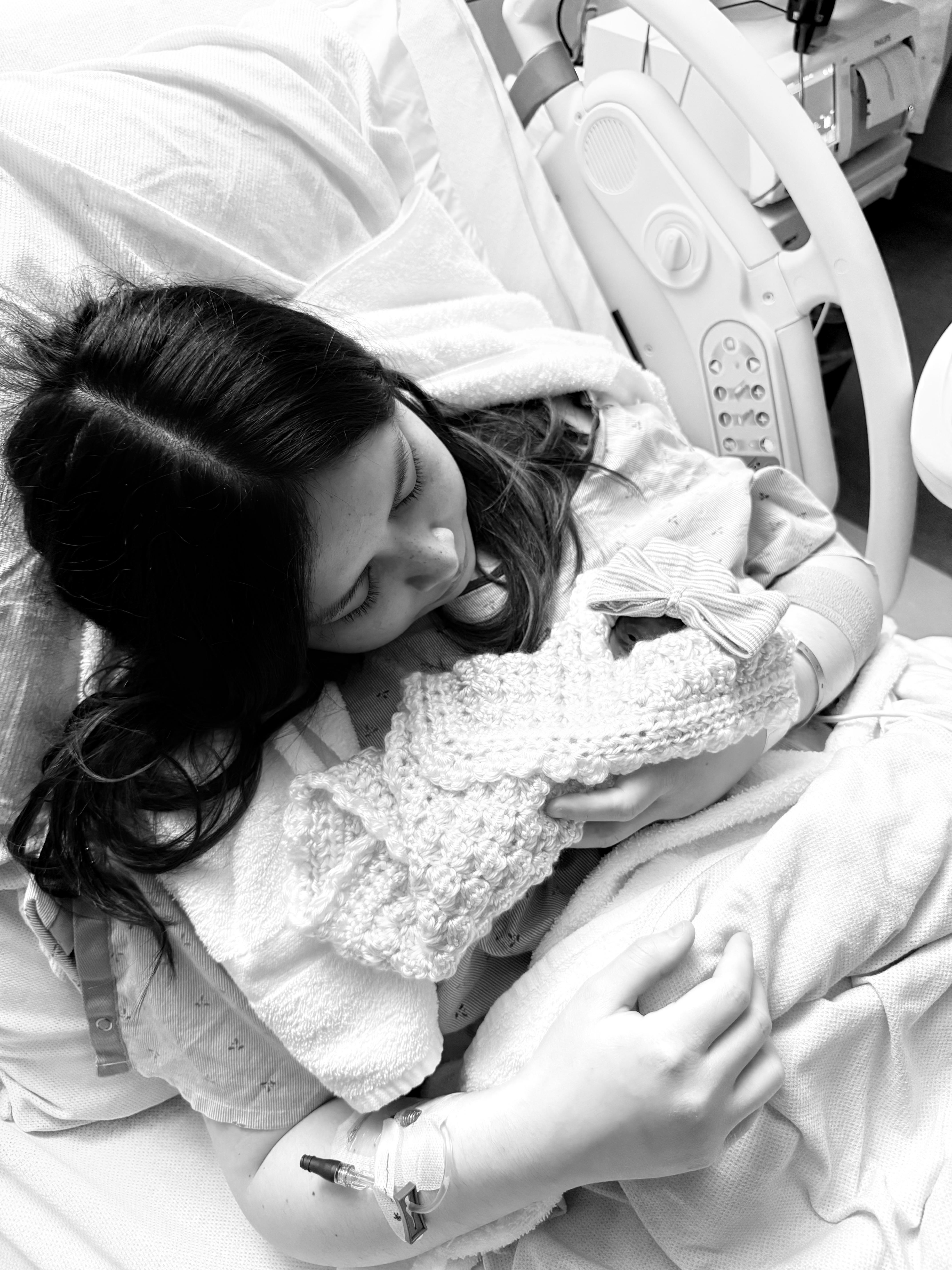 A woman holding a baby in a hospital bed