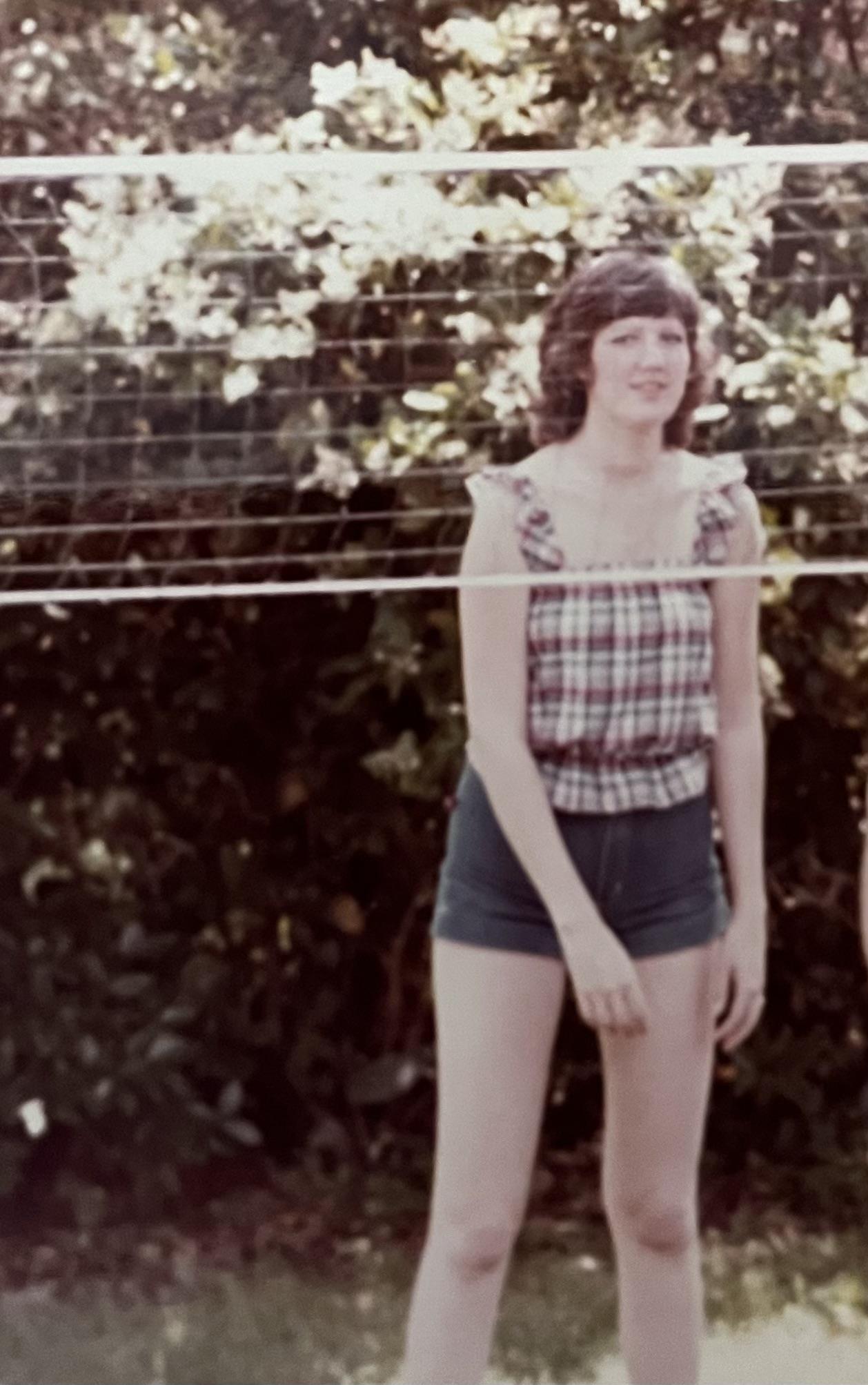 A woman standing next to a wire fence