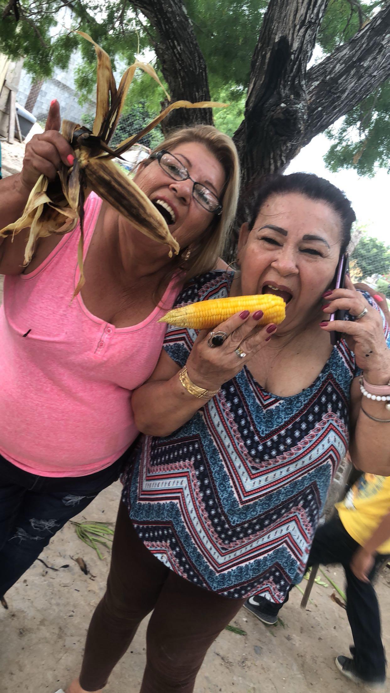Two women eating corn and talking on the phone