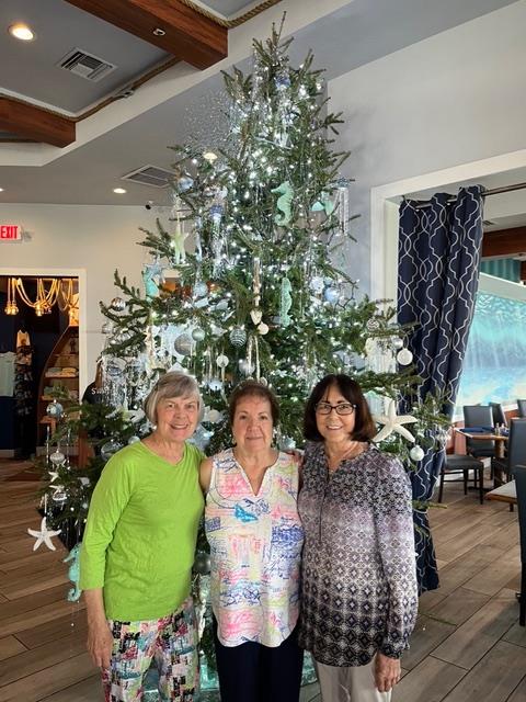 A group of women standing in front of a christmas tree