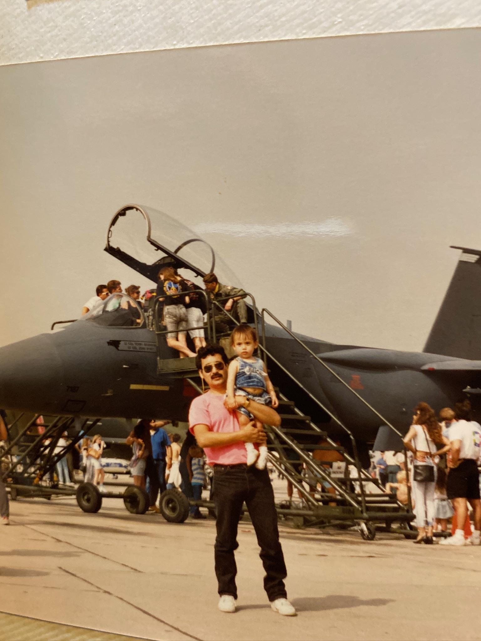 A man holding a child in front of a jet