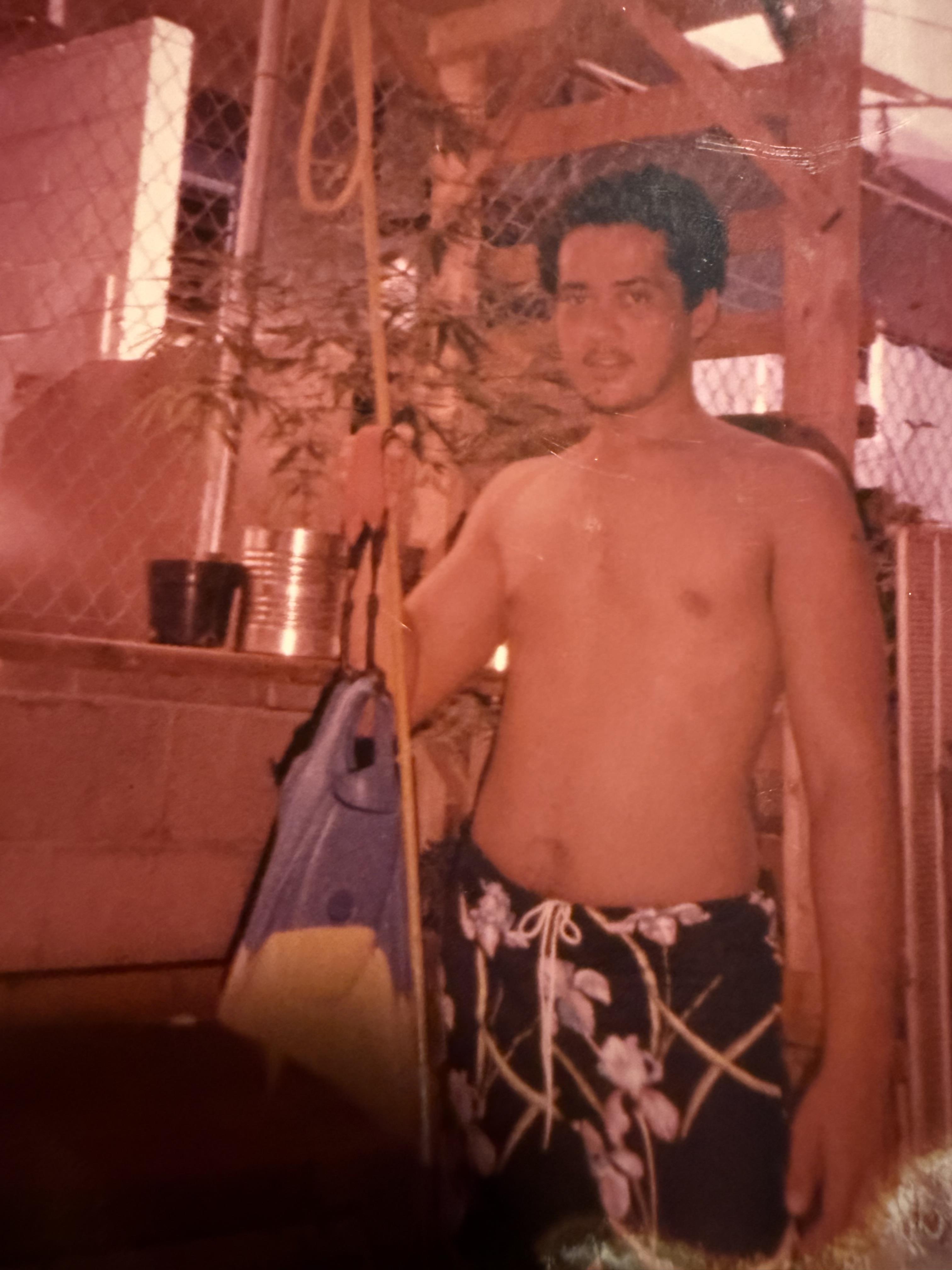 A man in swim trunks holding a surfboard