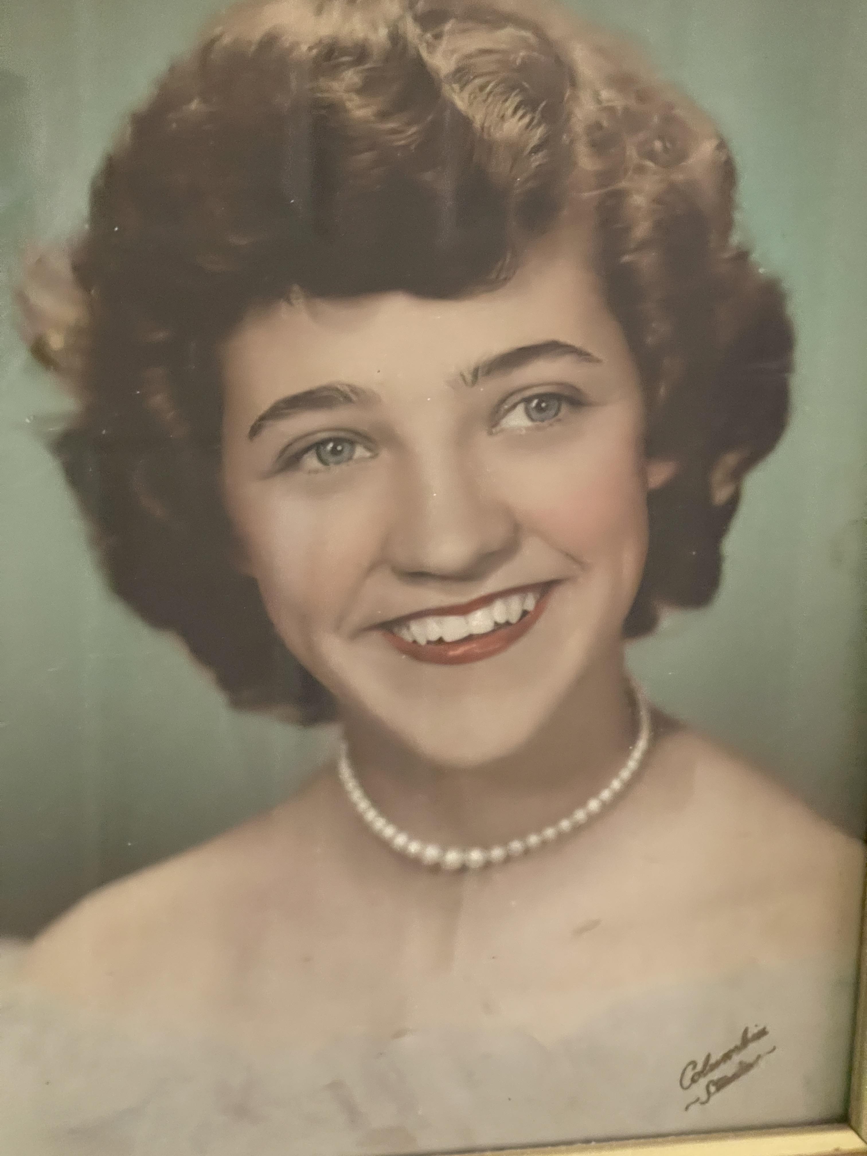 A woman smiling with a pearl necklace