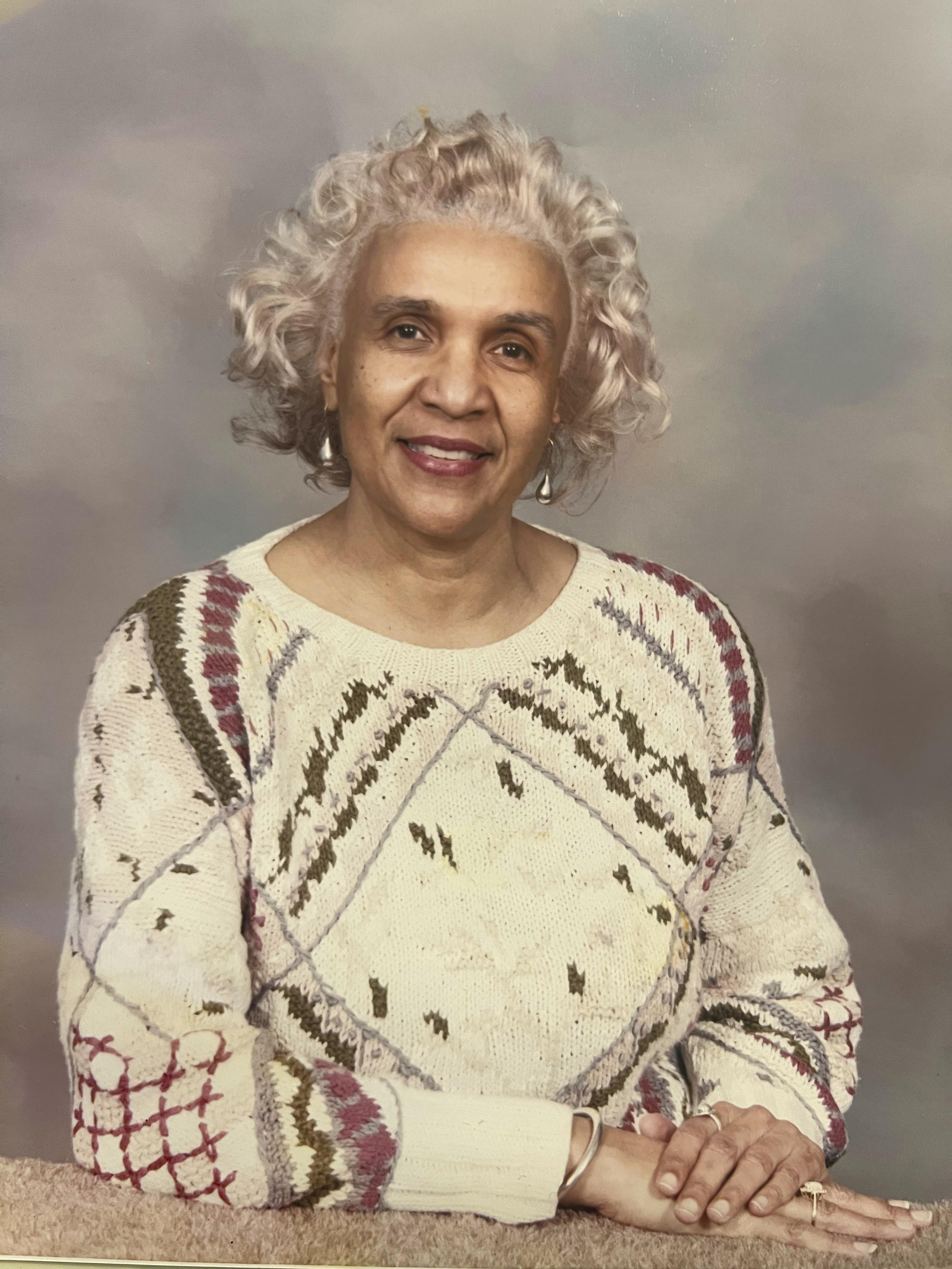 A woman with white hair wearing a sweater
