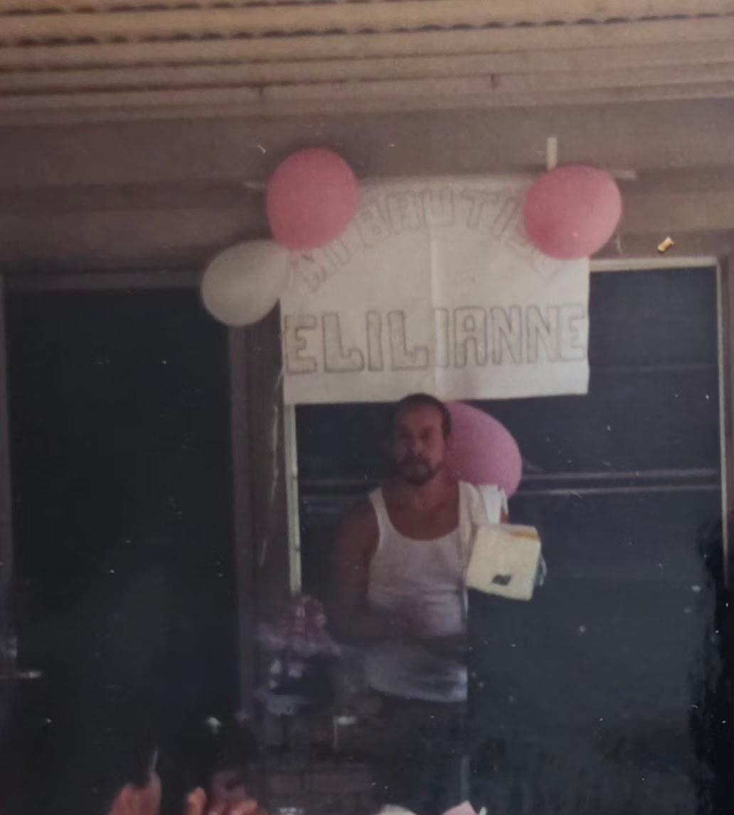 A man standing under a sign with balloons