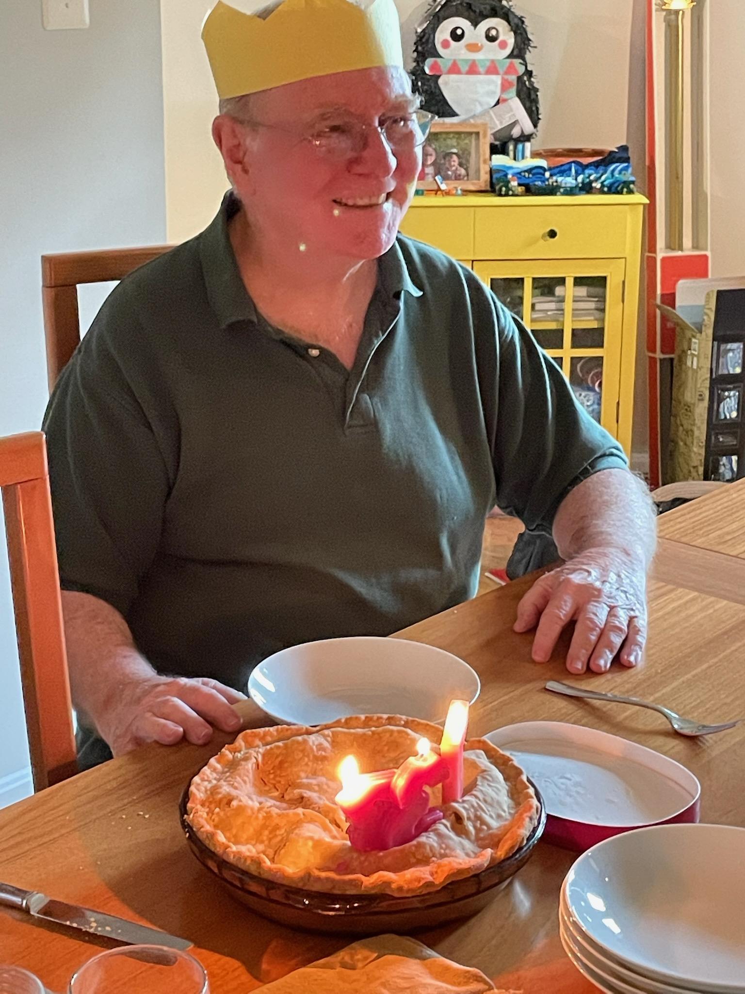 A man sitting at a table with a cake and a candle