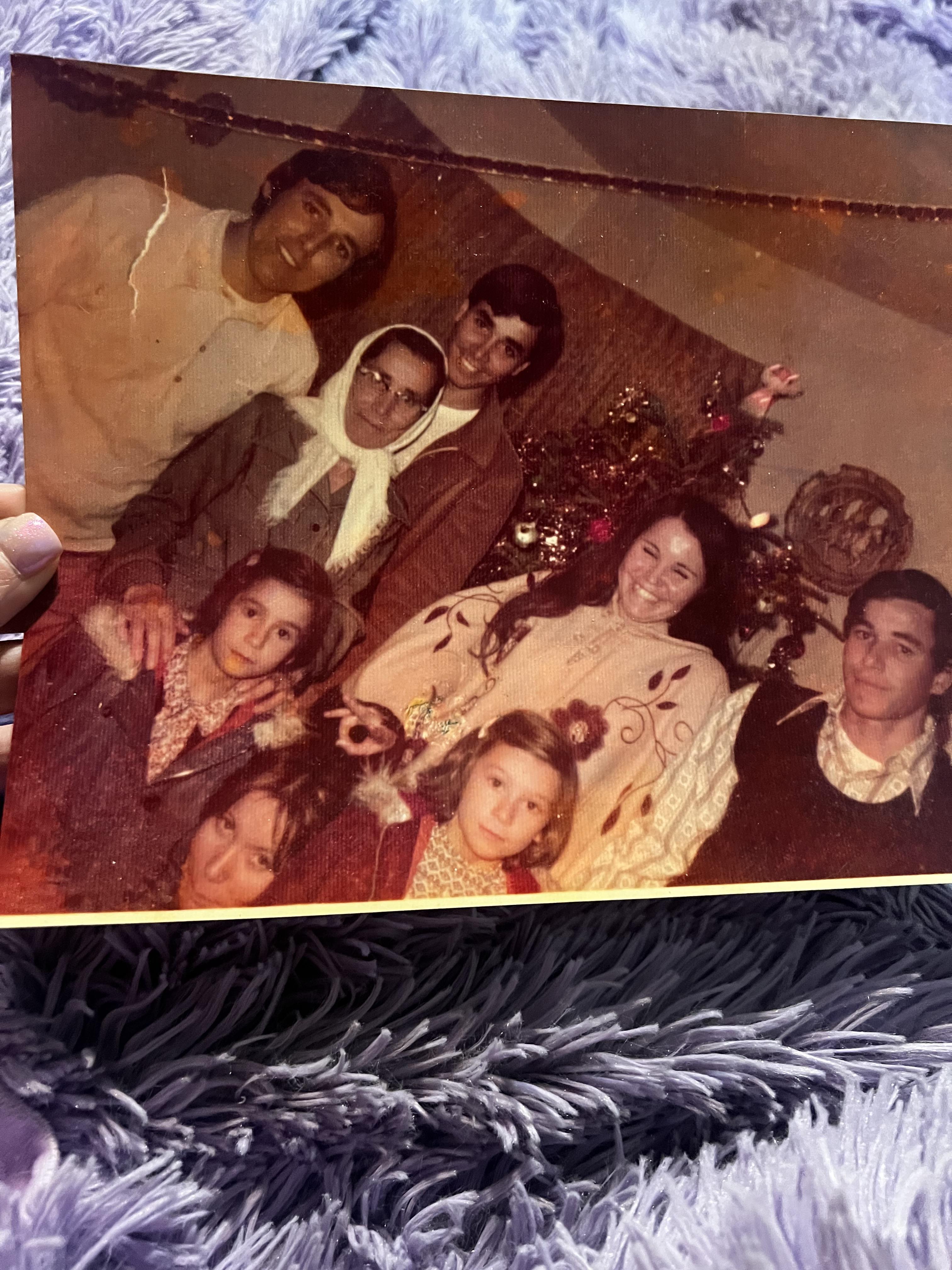 A hand holding a photo of a family