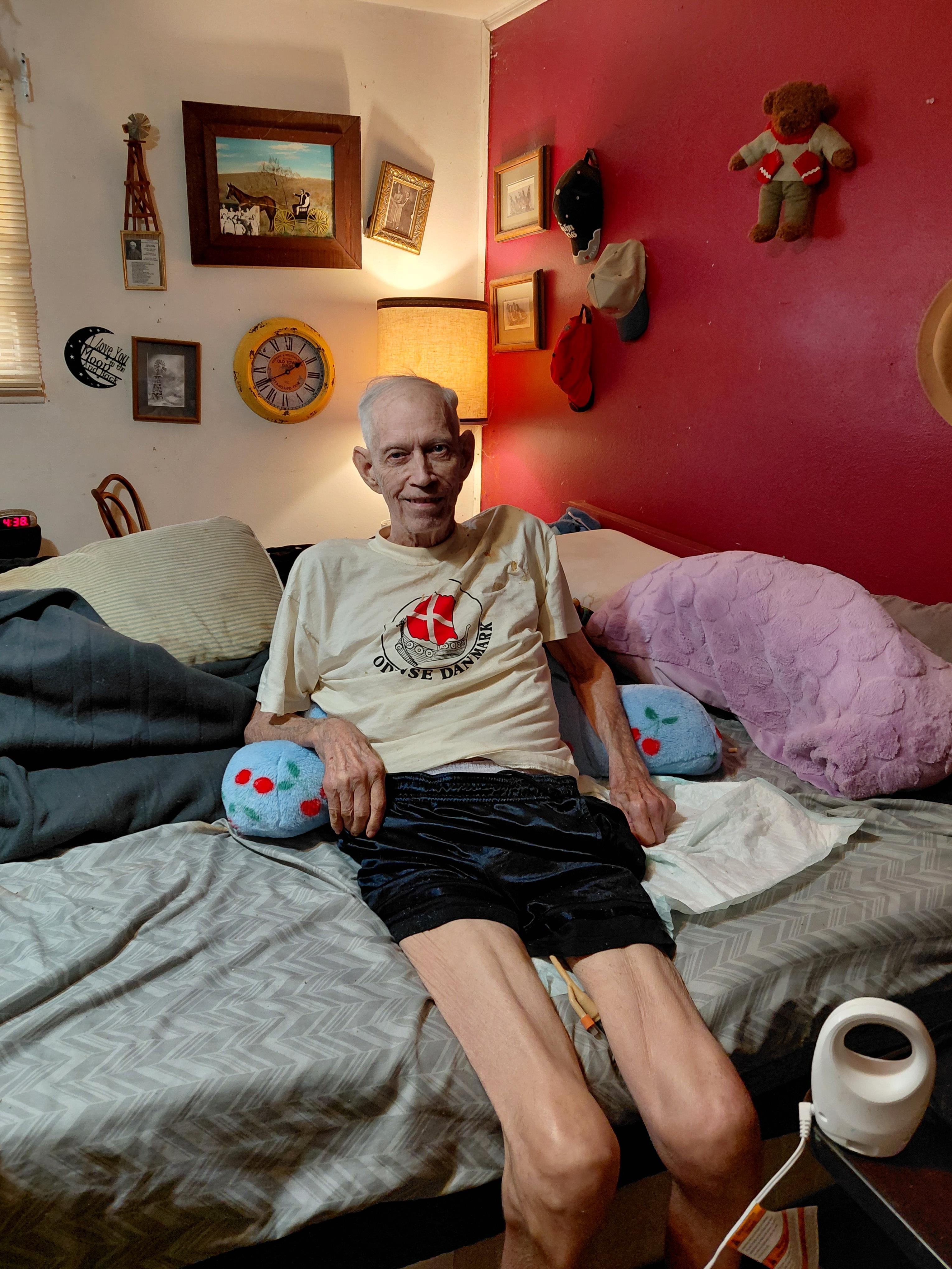 An old man sitting on a bed