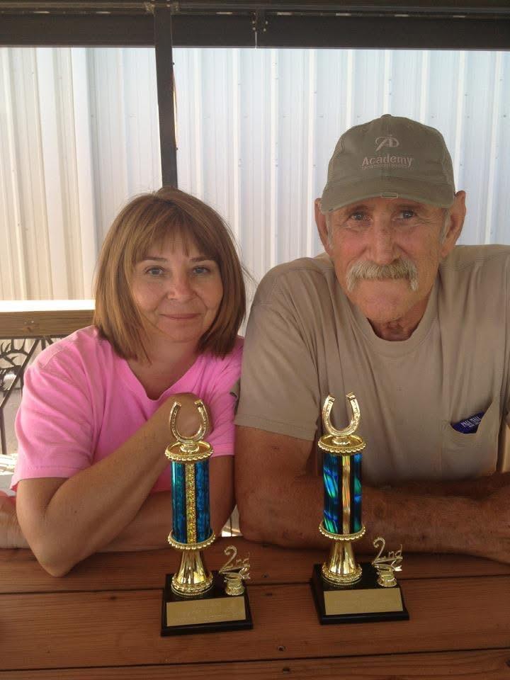 A man and woman sitting at a table with trophies