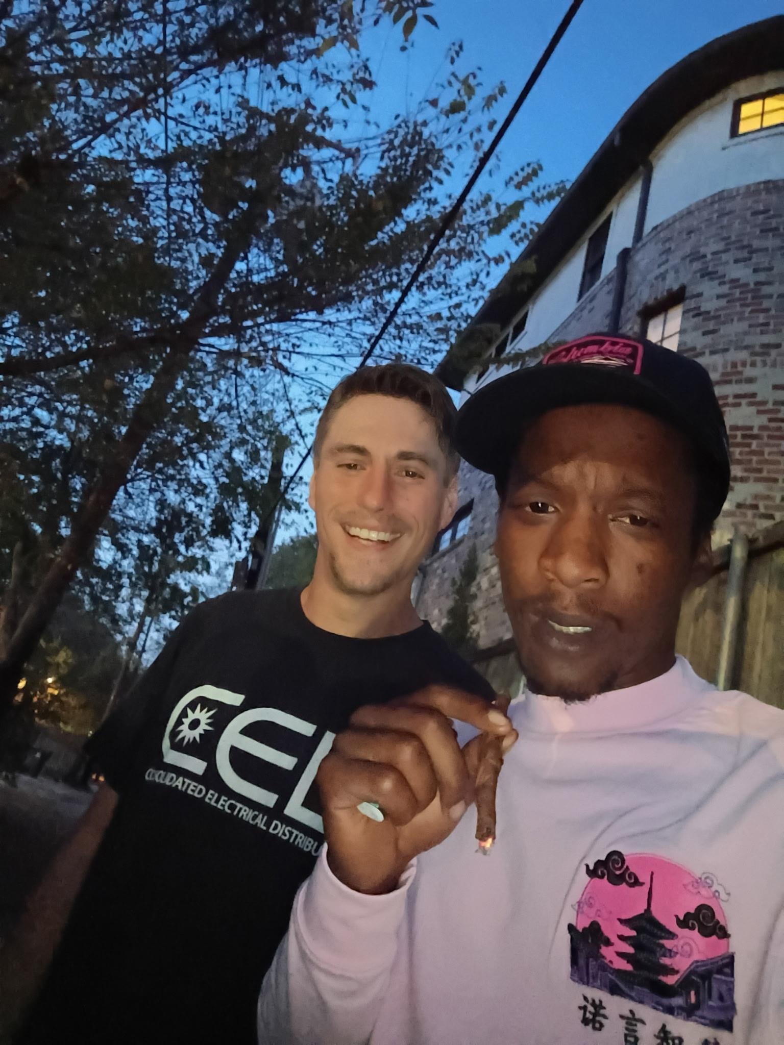 A man holding a cigarette and smiling at the camera