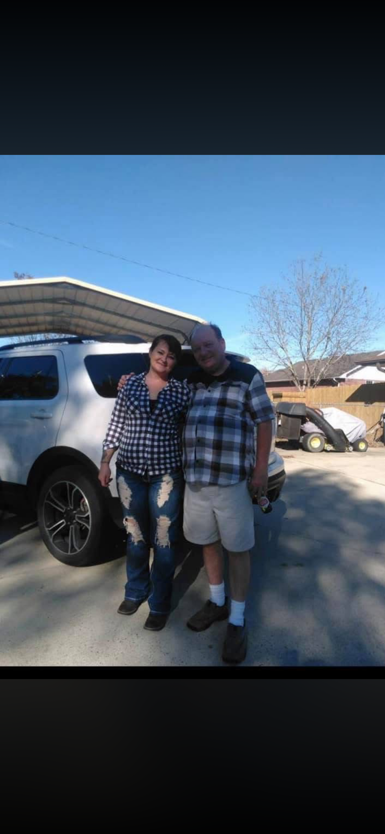 A man and woman standing in front of a car