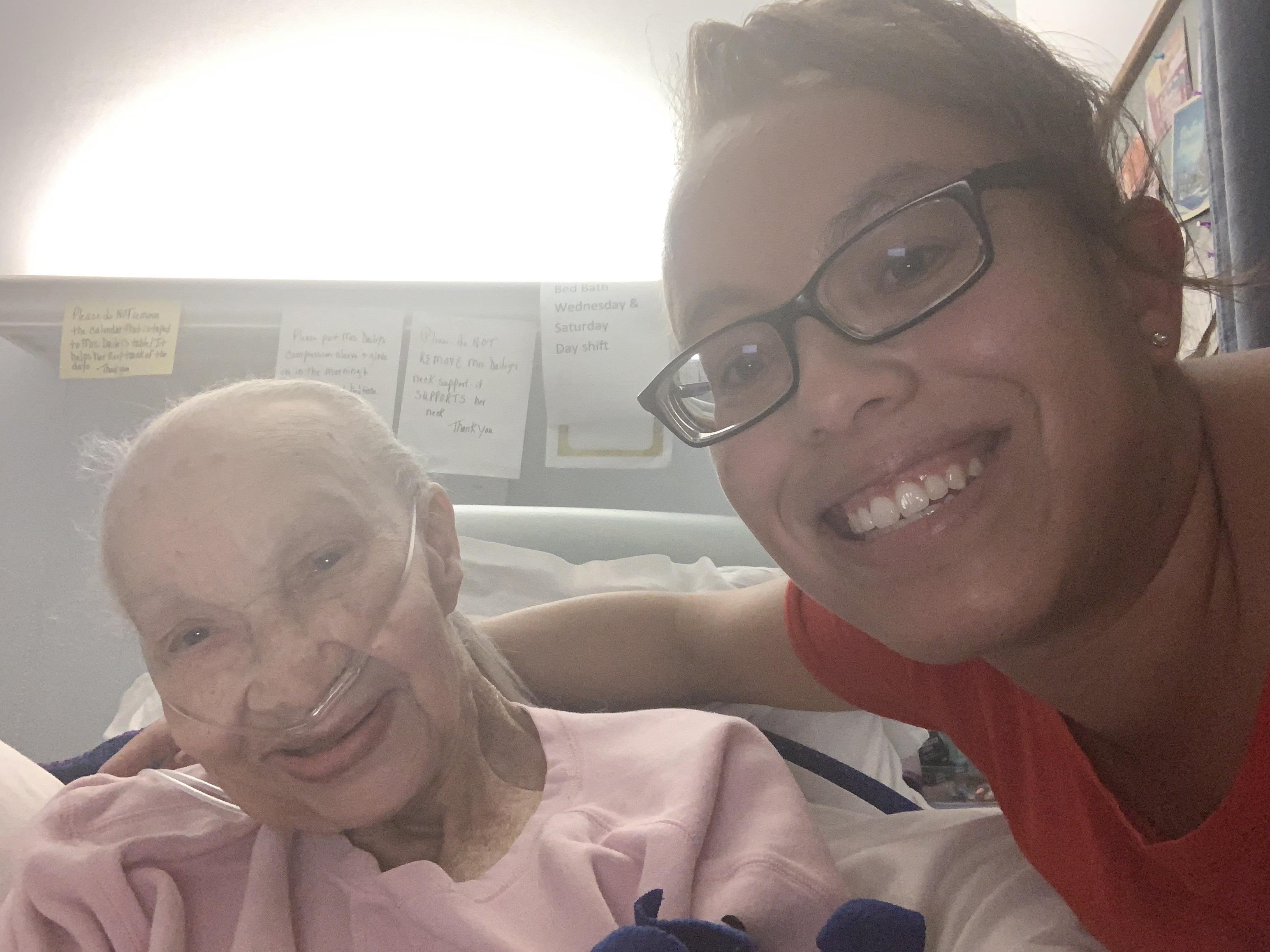 A woman smiling next to a woman in a hospital bed
