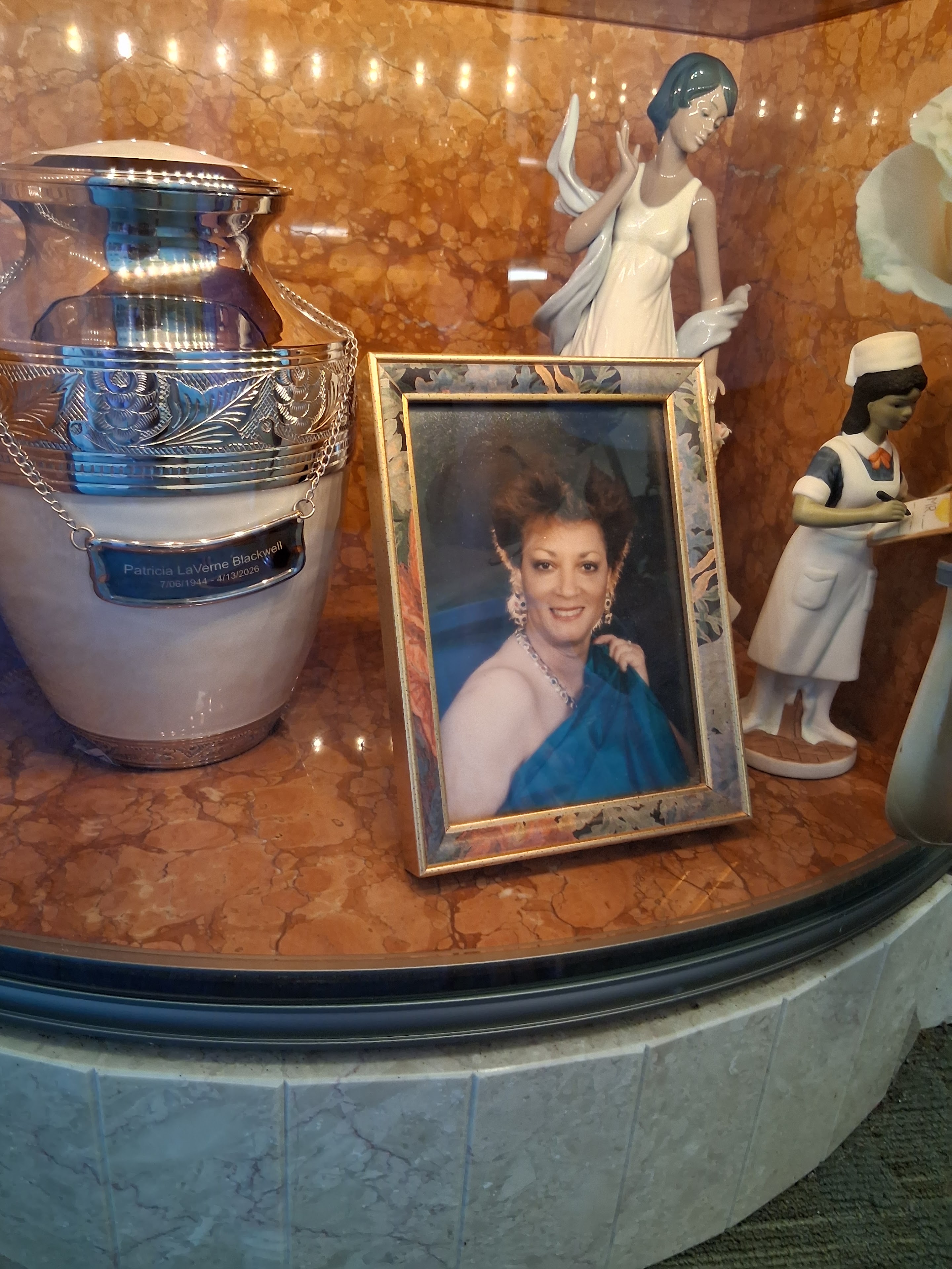 A picture of a woman in a frame next to a urn and a vase