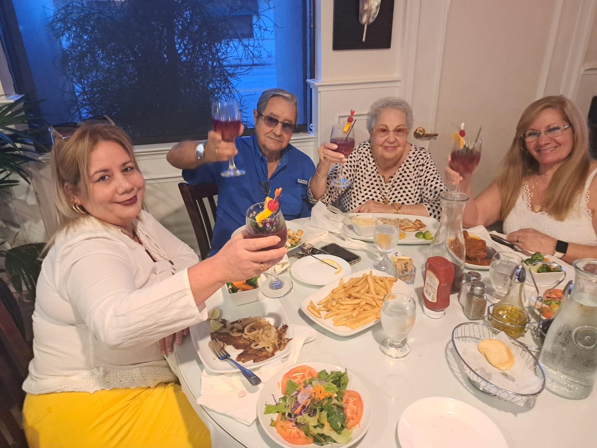 A group of people sitting at a table with food and drinks
