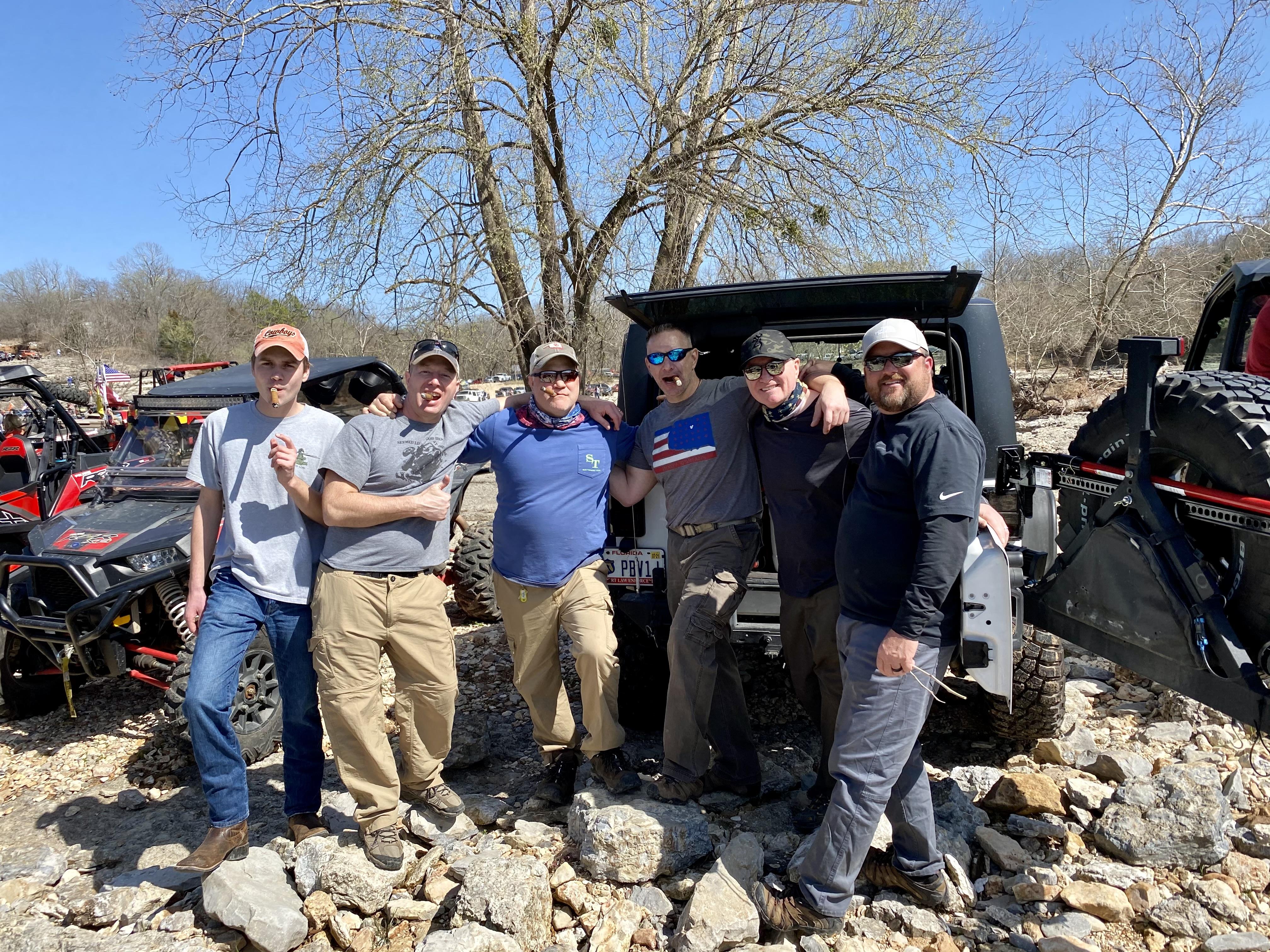 A group of men posing for a photo in front of a jeep