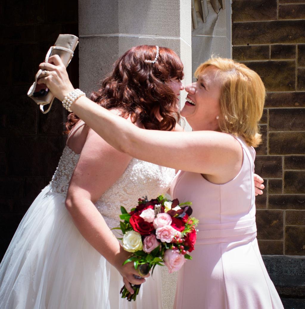 Two women in white dresses hugging