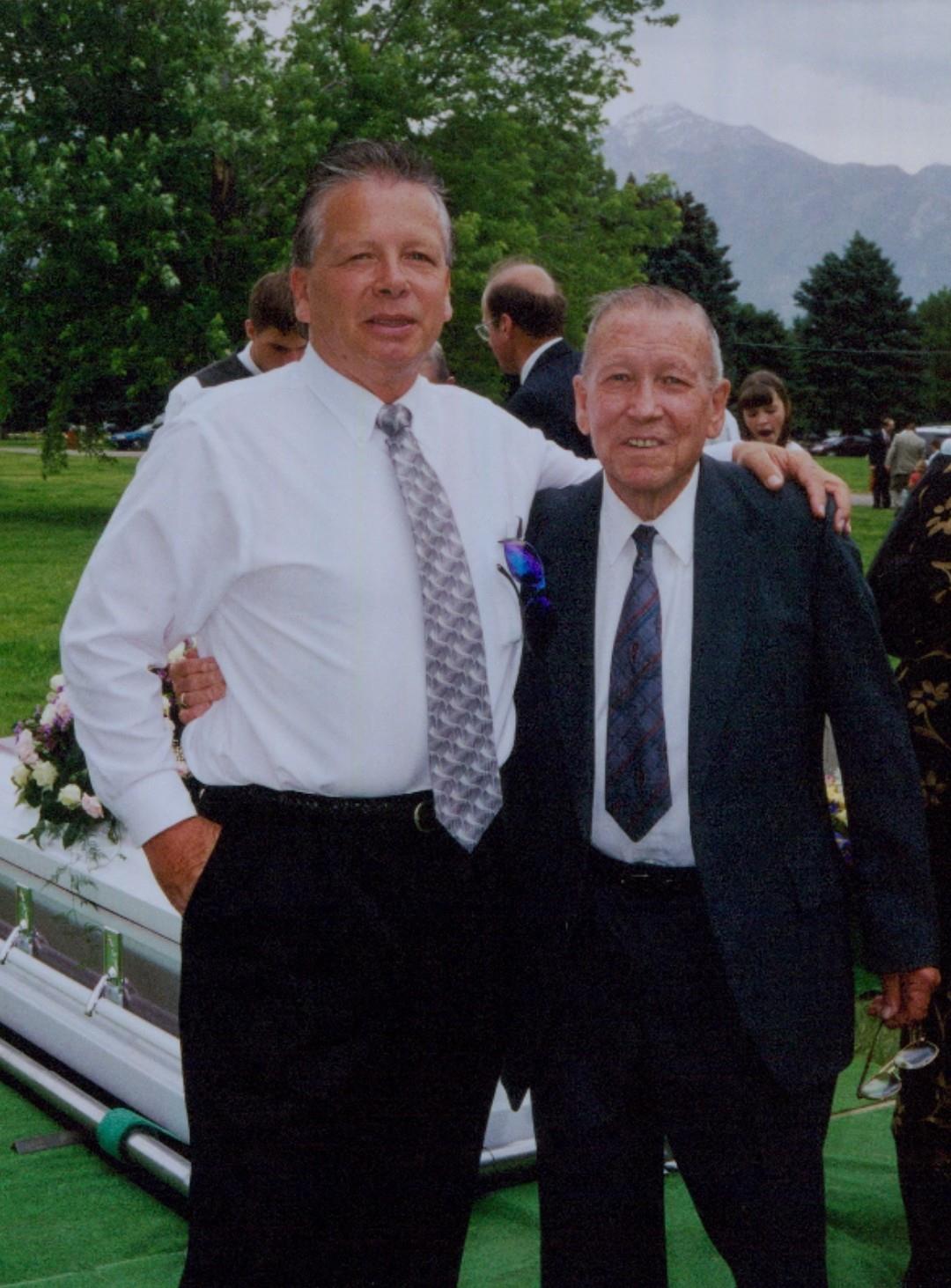 A man in a suit and tie standing next to a coffin
