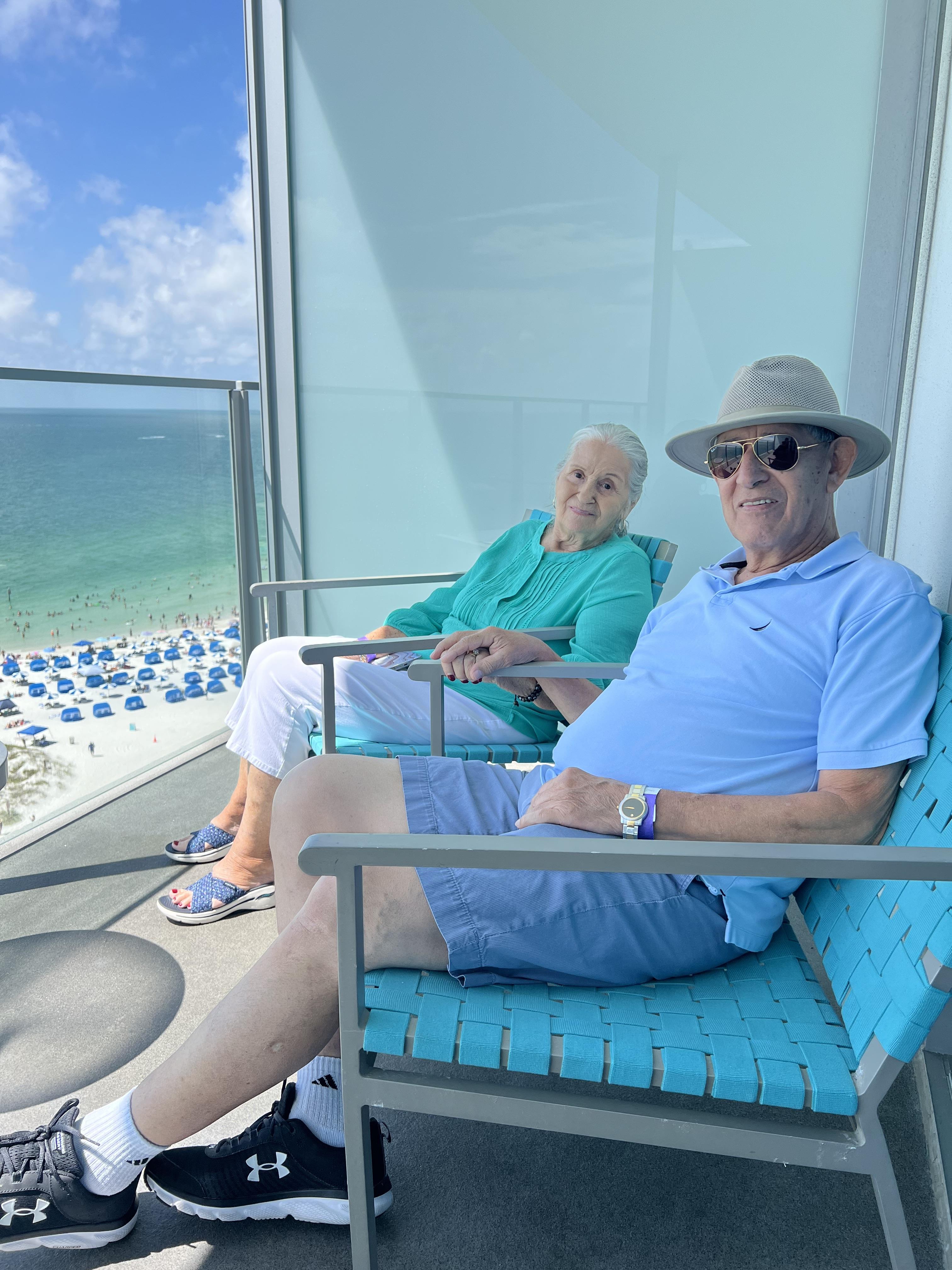 A man and woman sitting in chairs on a balcony
