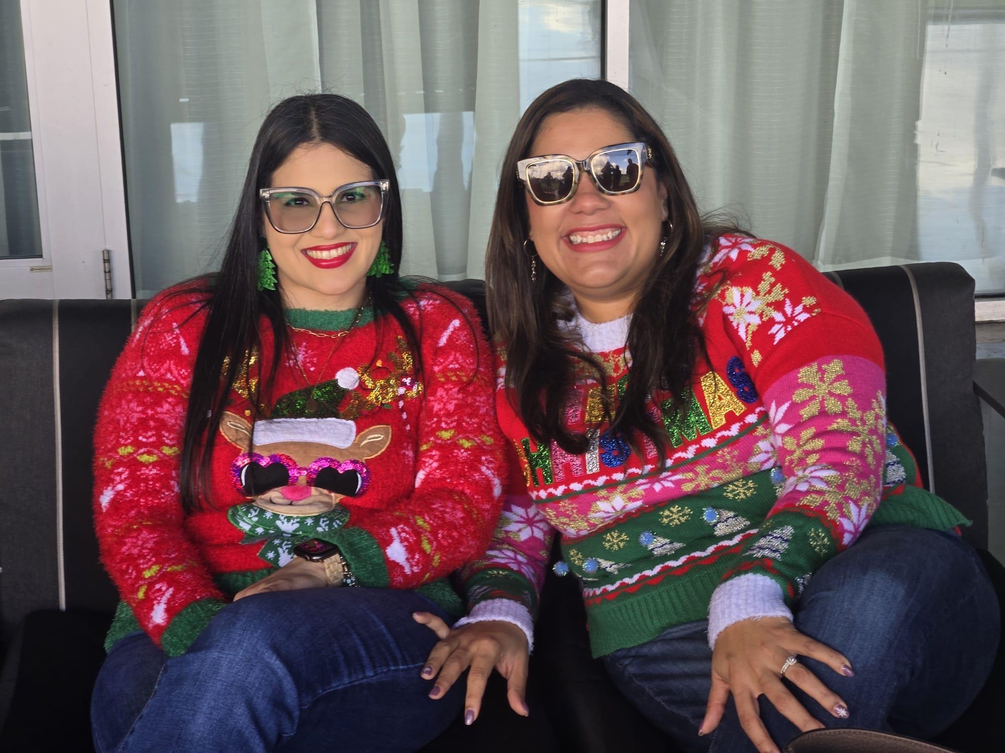 Two women wearing christmas sweaters and sunglasses