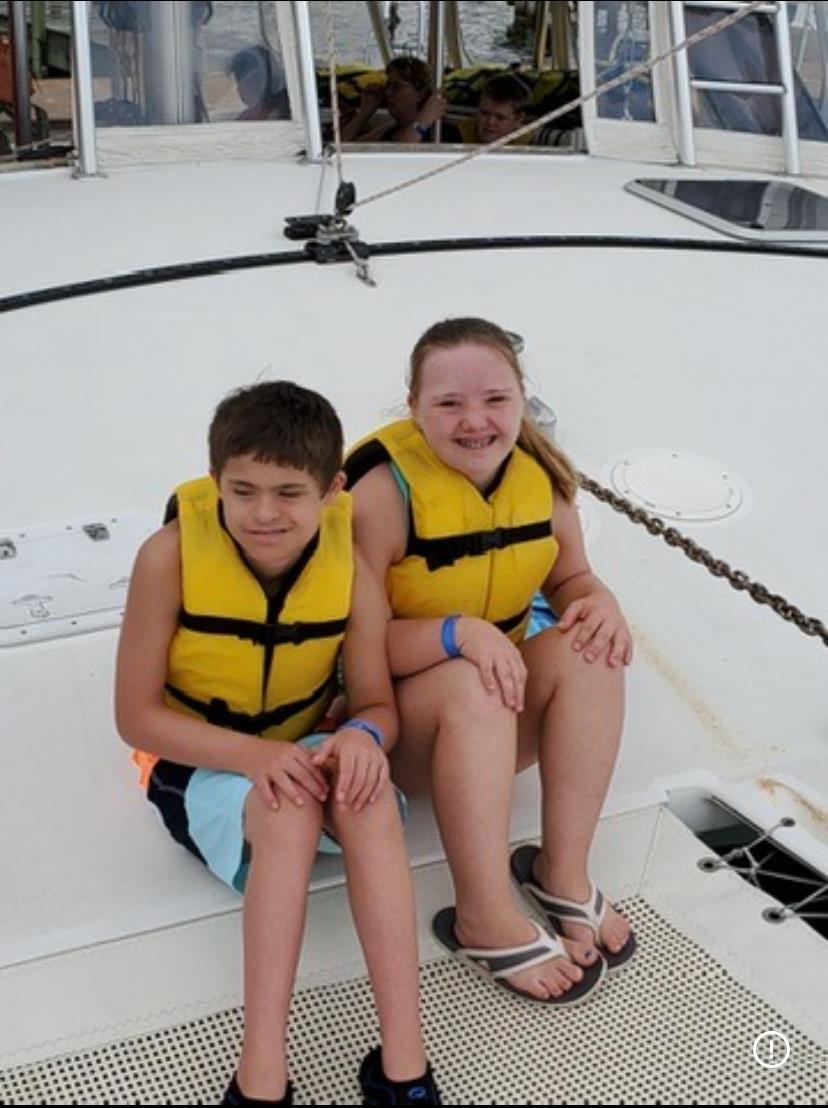 A boy and girl wearing life jackets on a boat