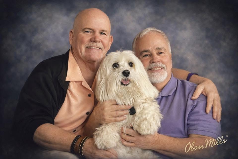 Two men holding a dog