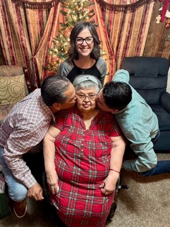 A group of people kissing an old woman