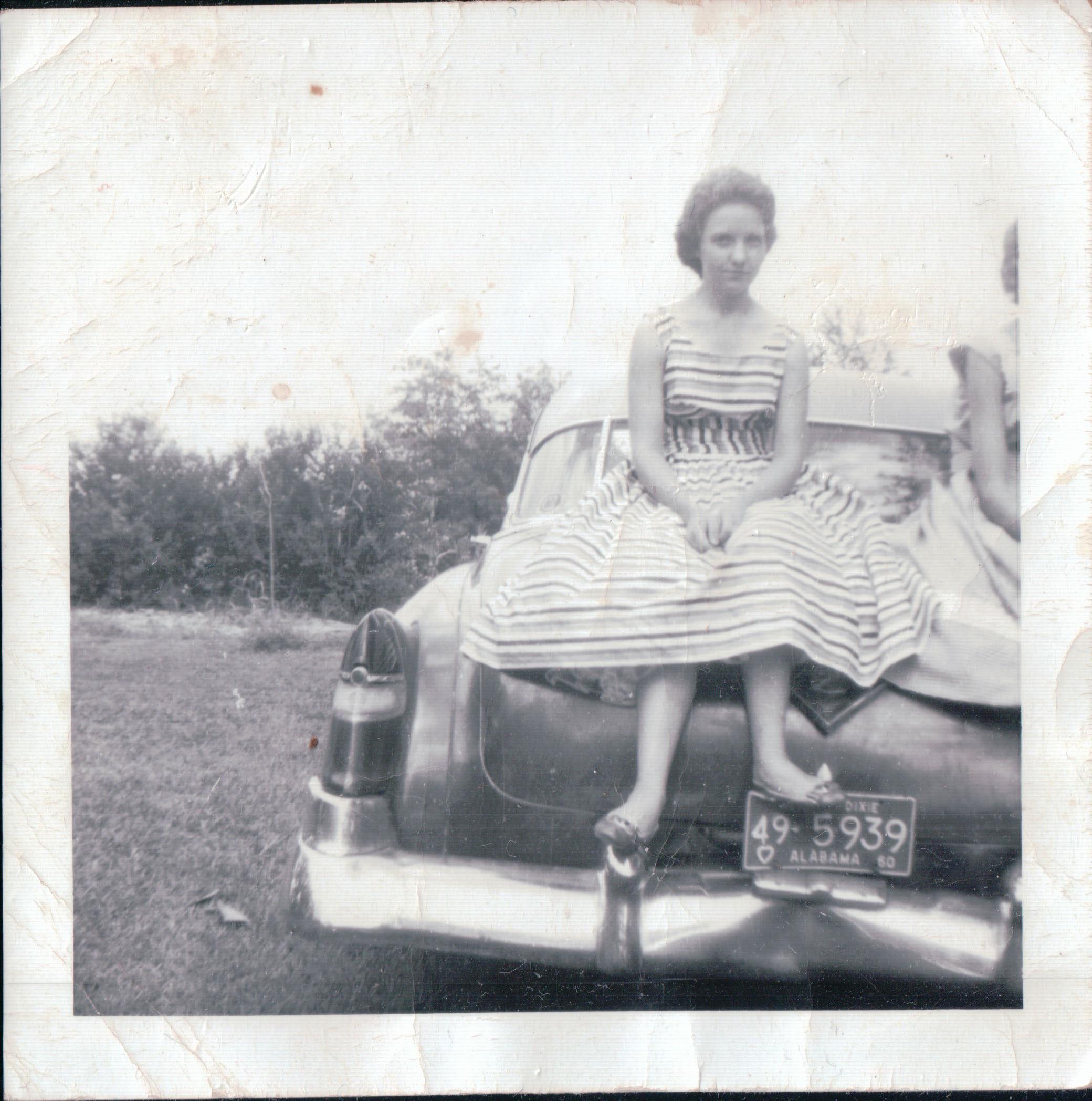 A woman sitting on the back of a car