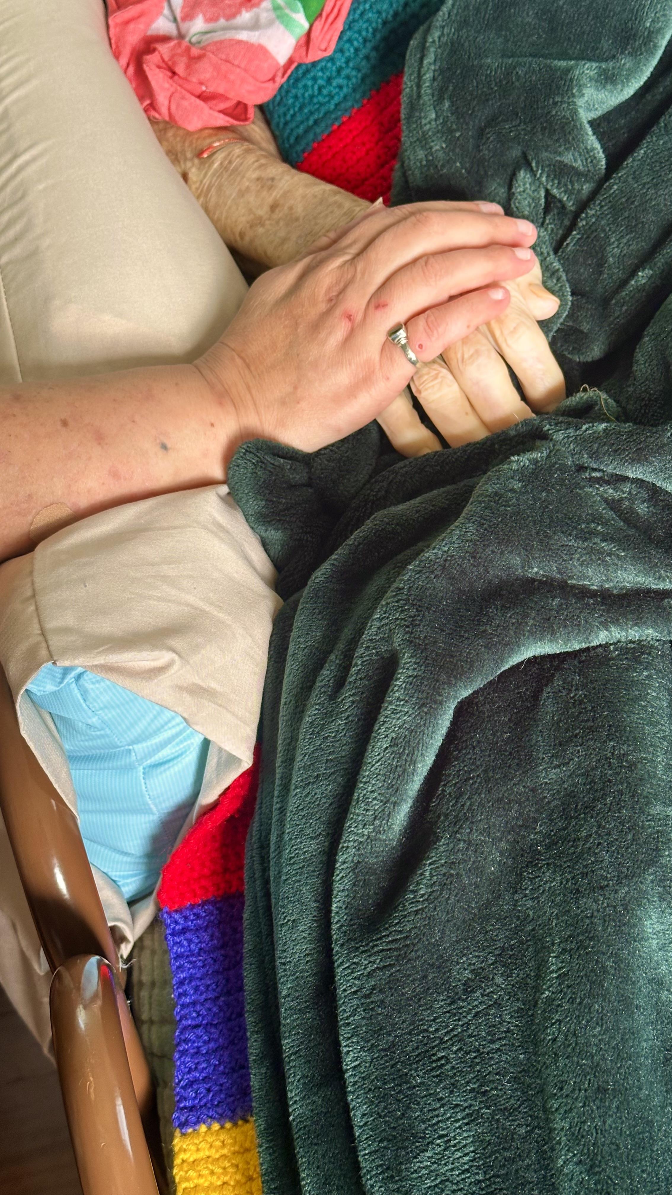 A person lying down with a blanket and hands on their hands