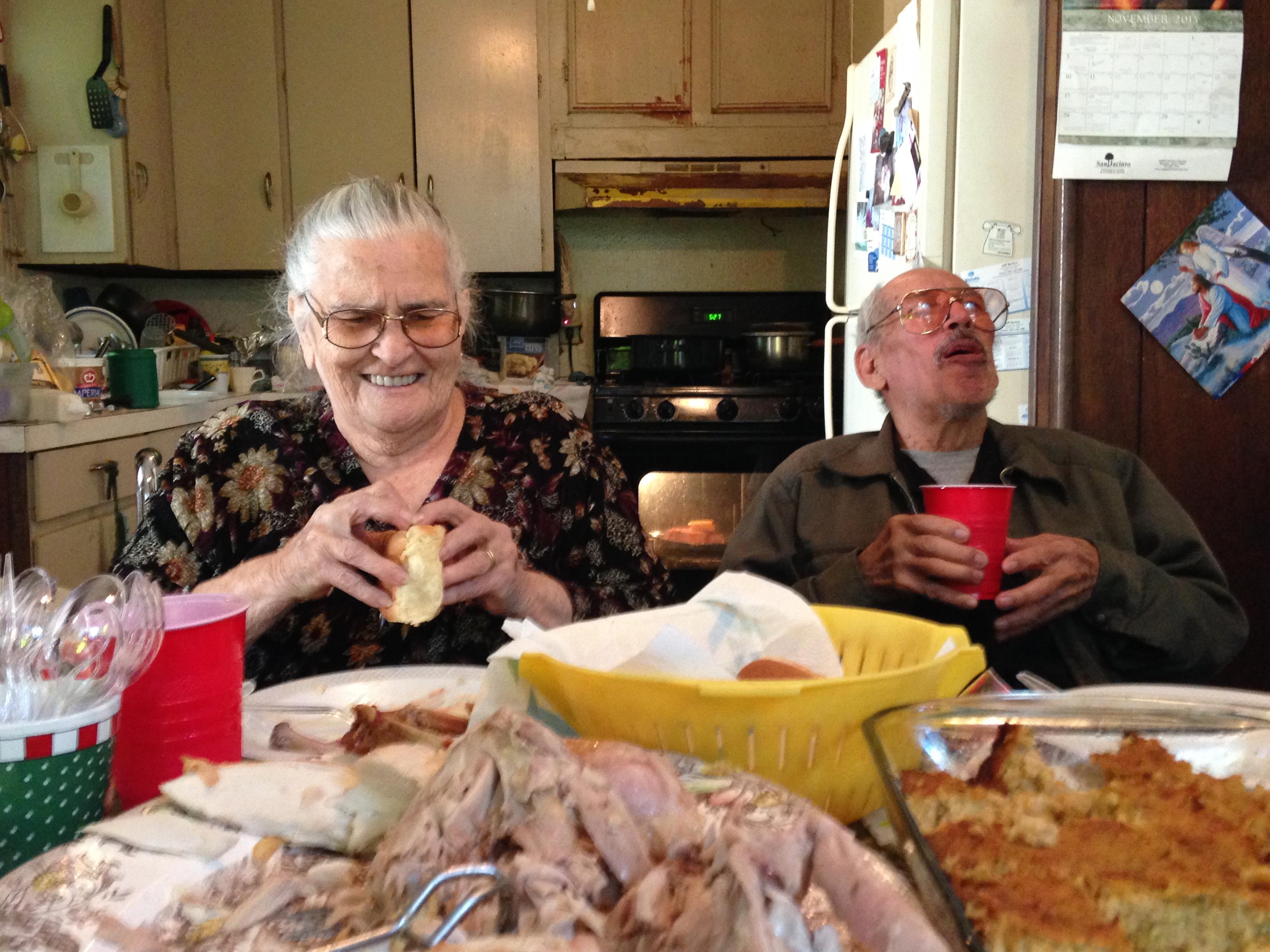 A man and woman eating in a kitchen