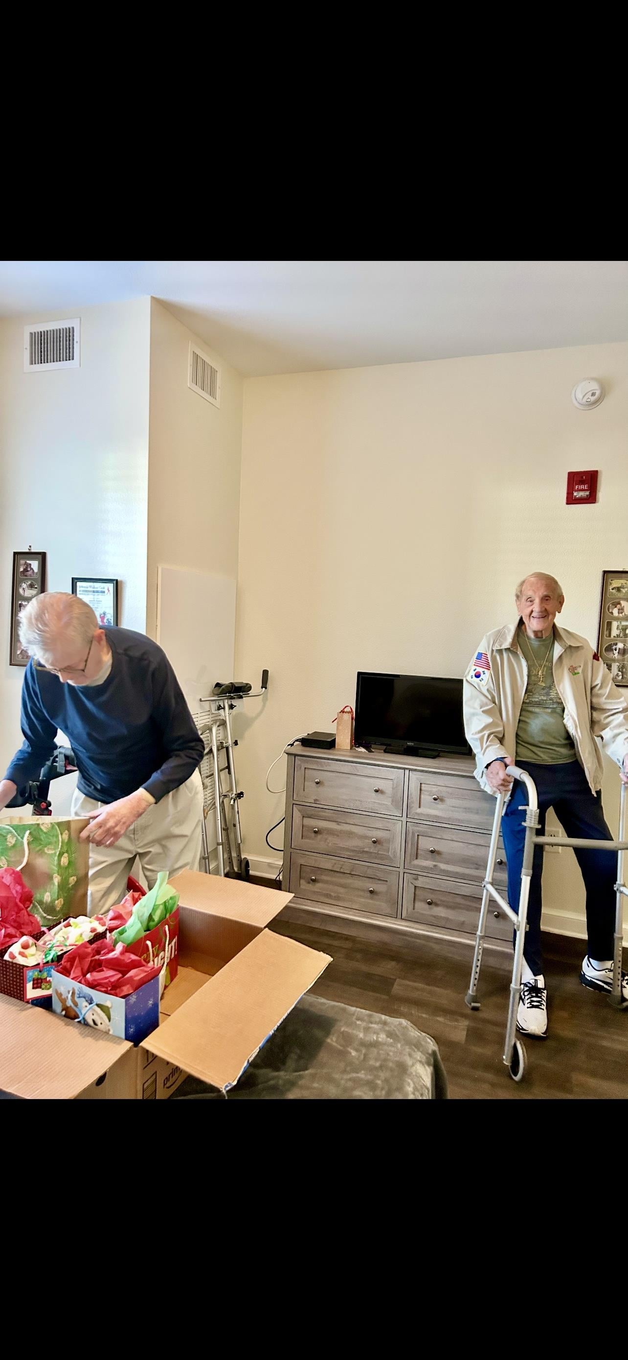 Two men in a room with a box of presents