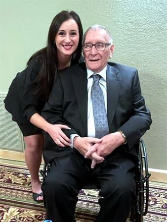 A woman hugging an old man in a wheelchair