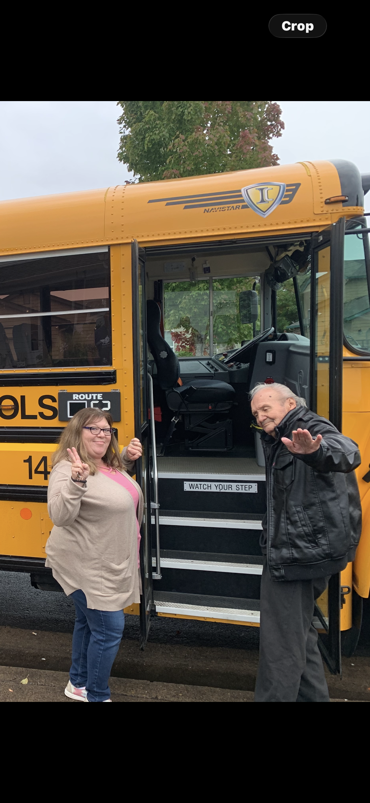 A man and woman standing next to a school bus