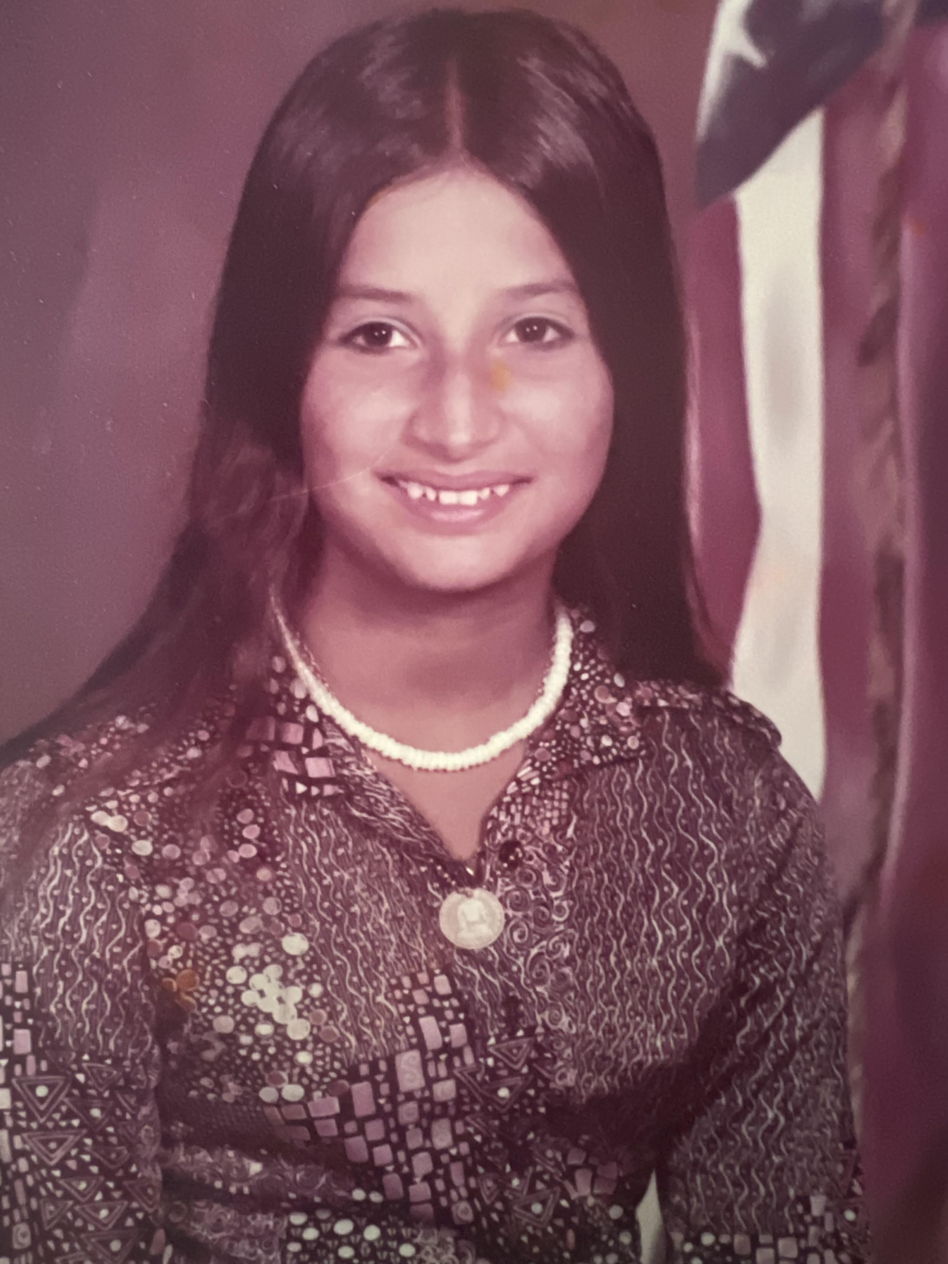 A girl with long hair wearing a necklace and a pearl necklace