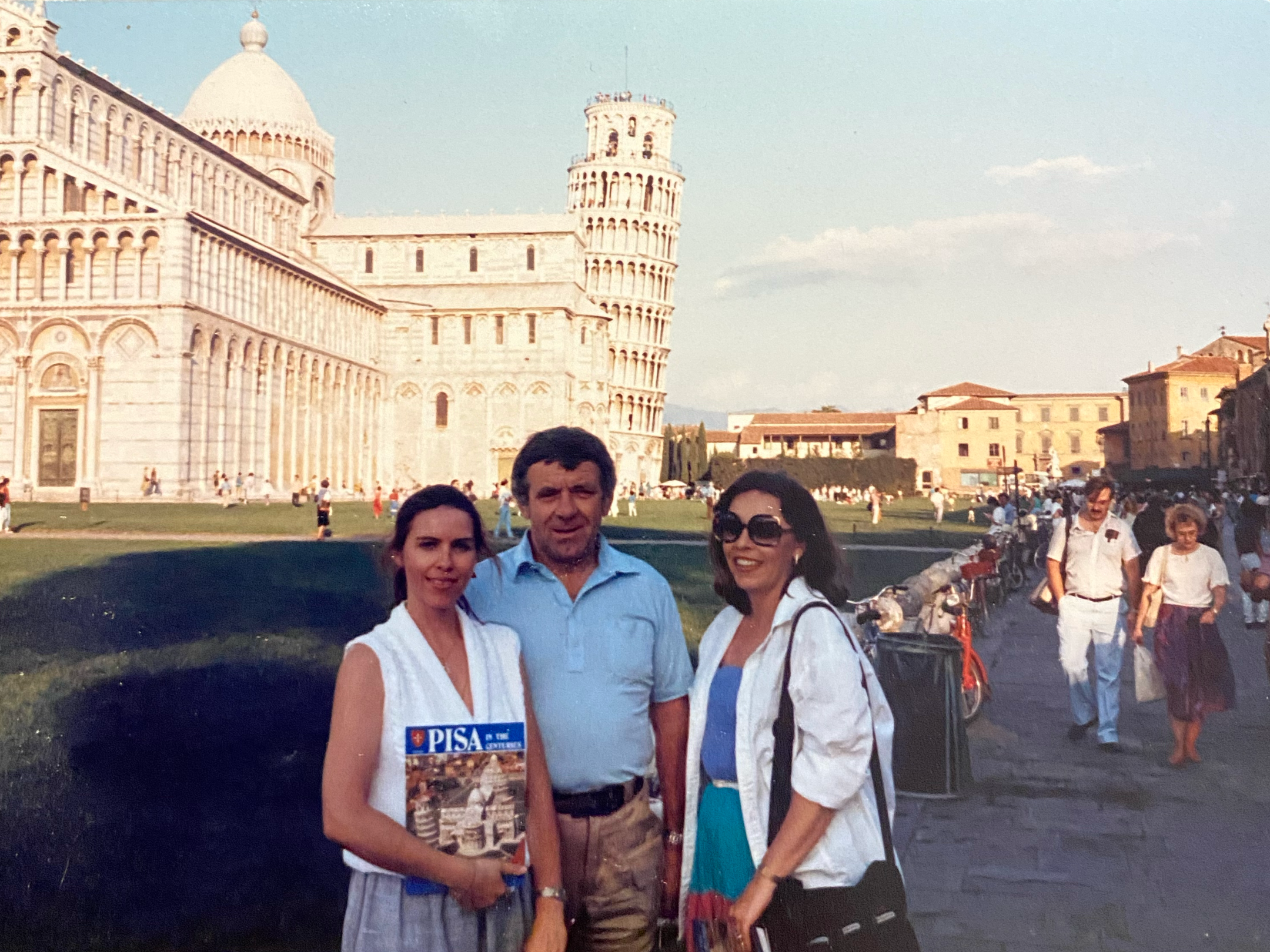 A group of people posing for a picture in front of a leaning tower