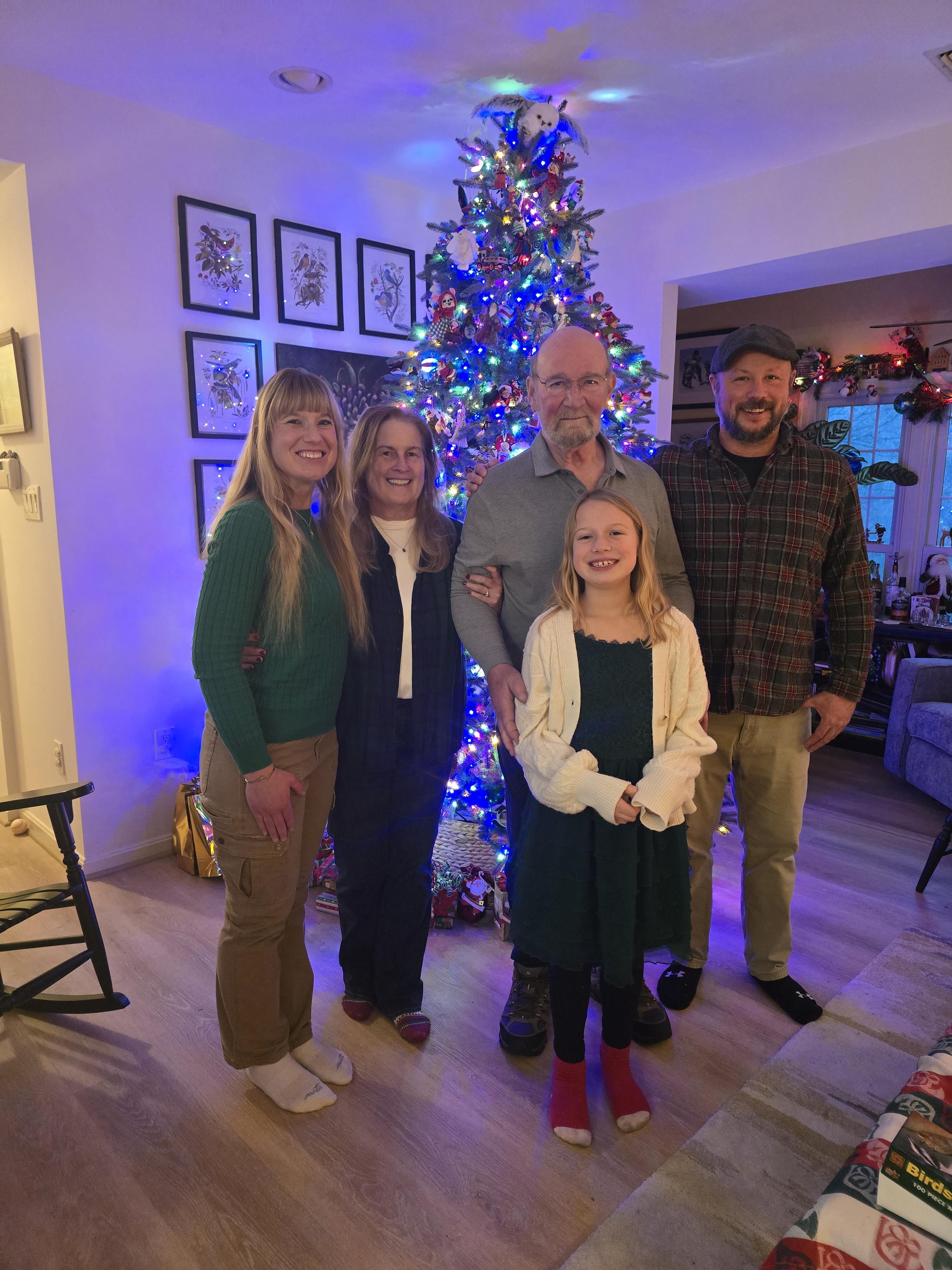 A group of people posing for a photo in front of a christmas tree