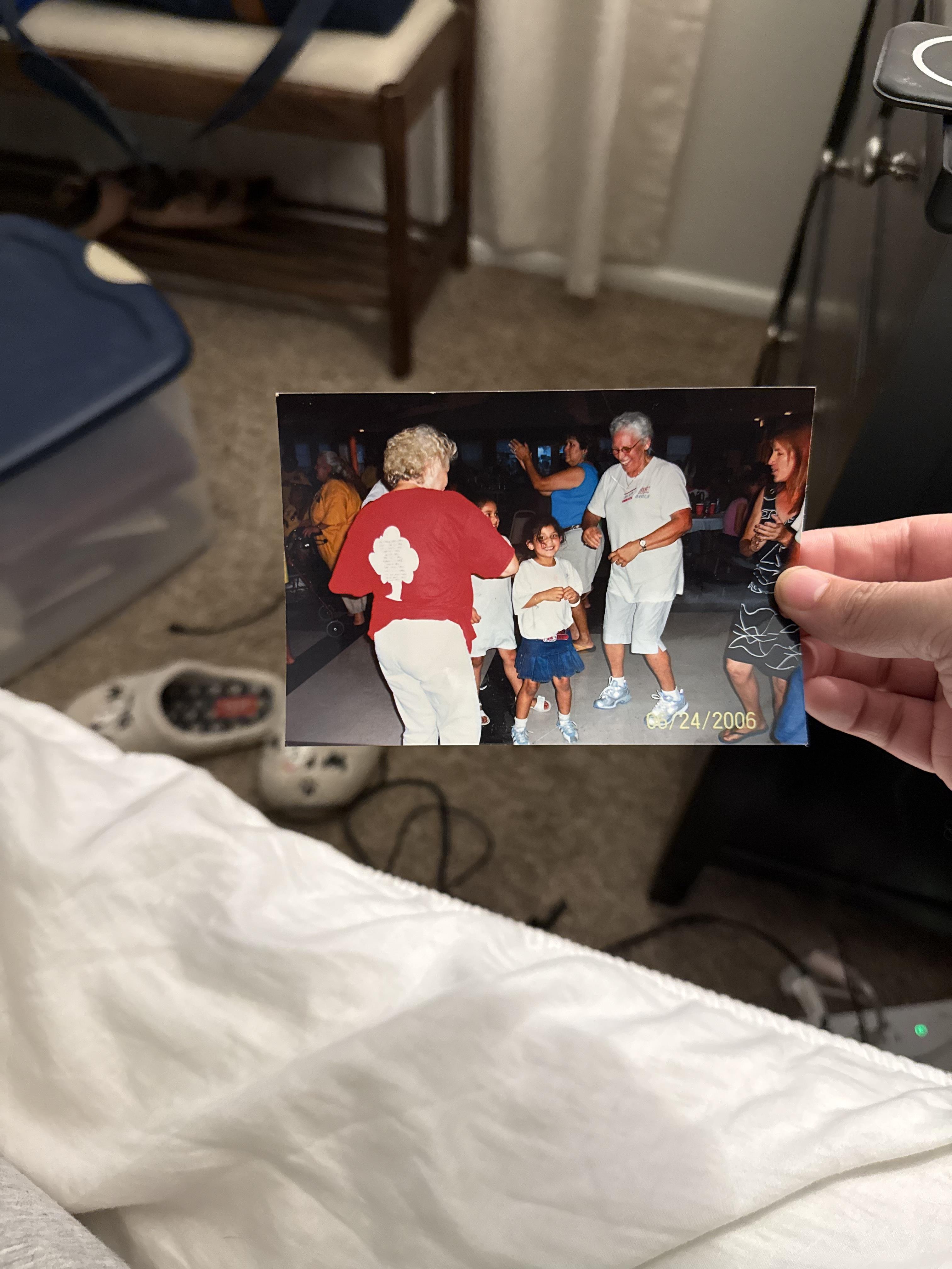 A hand holding a photo of a family