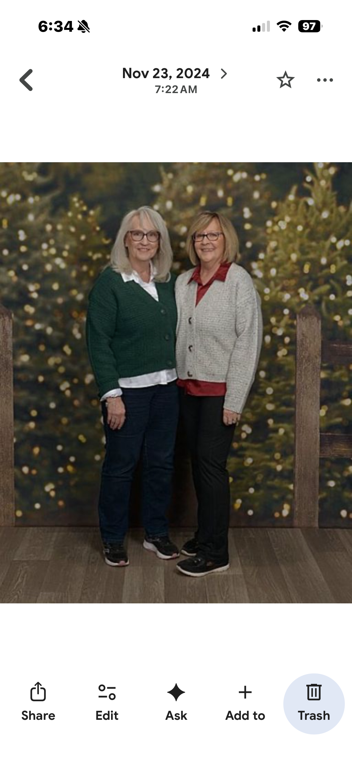 Two women standing together in front of a fence
