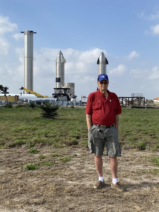 A man standing in a field with rockets in the background