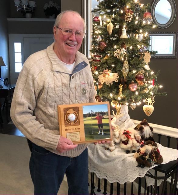 A man holding a picture frame in front of a christmas tree