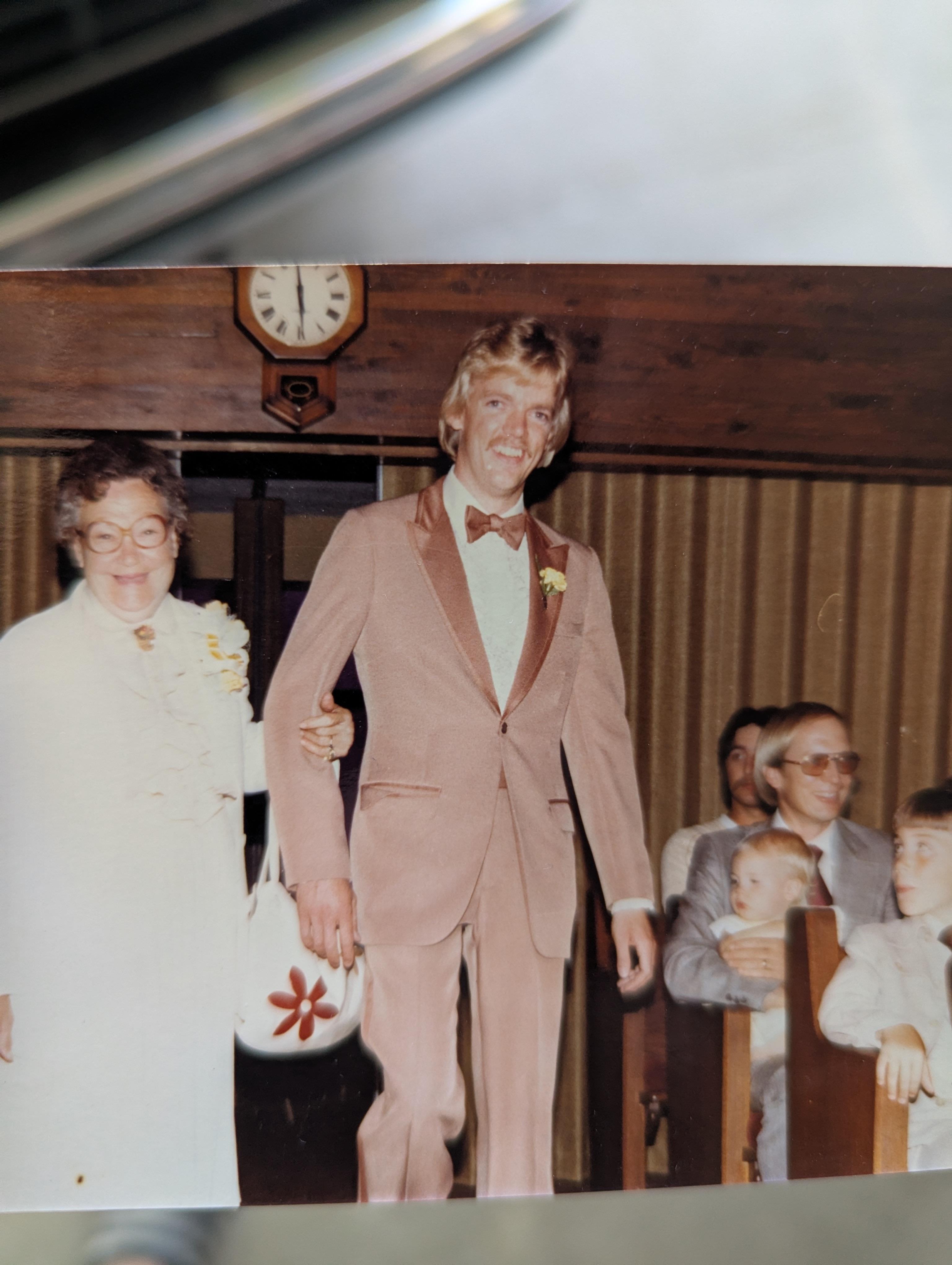 A man in a suit and bow tie walking down the aisle