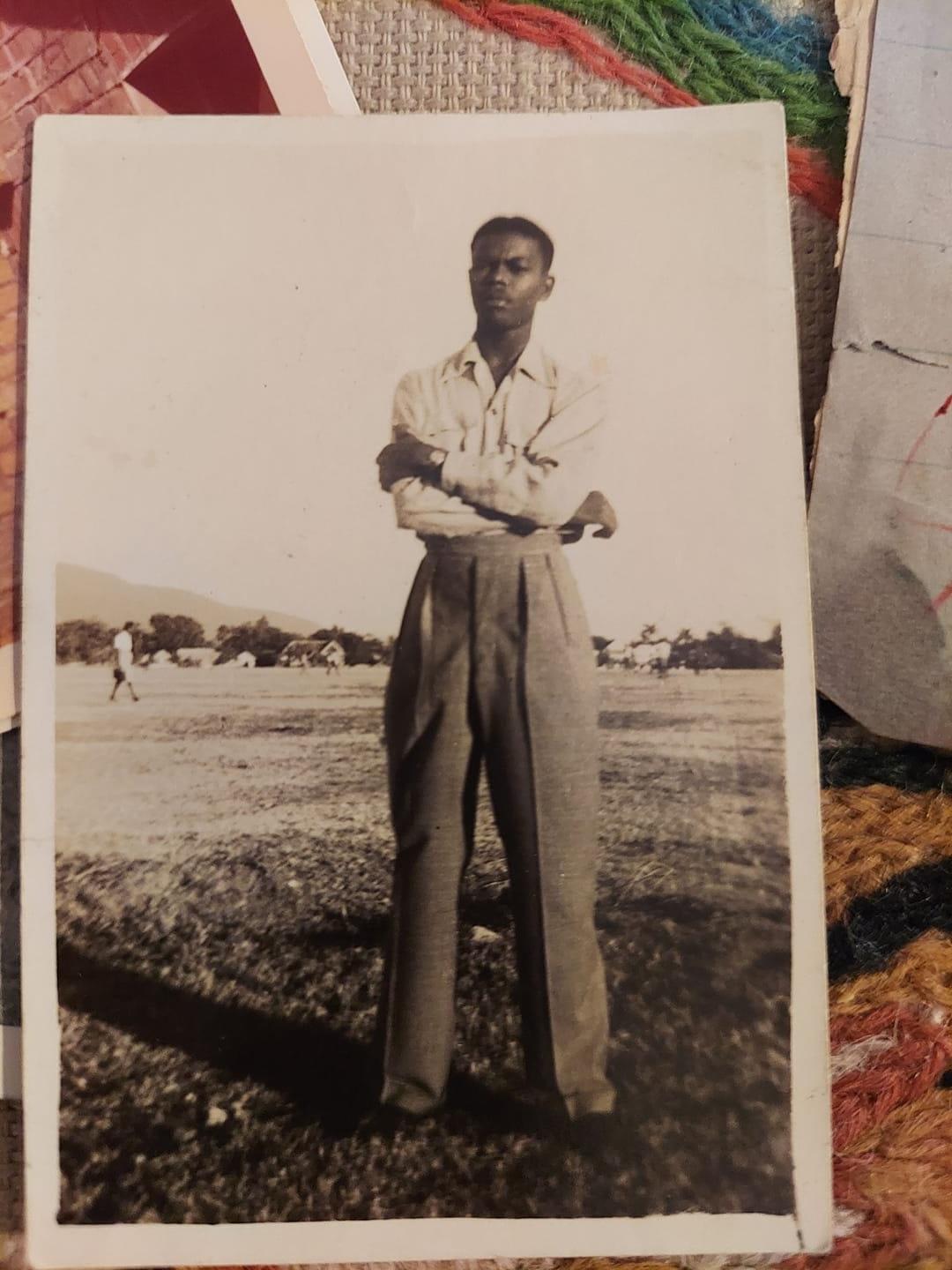 A black and white photo of a man standing with his arms crossed