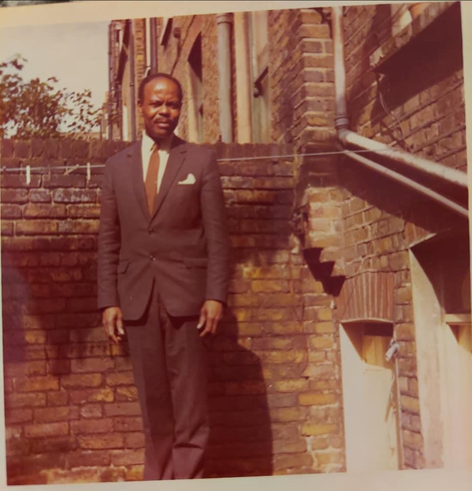 A man in a suit standing in front of a brick wall