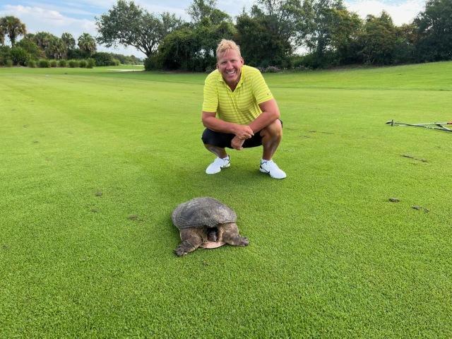 A man kneeling next to a turtle