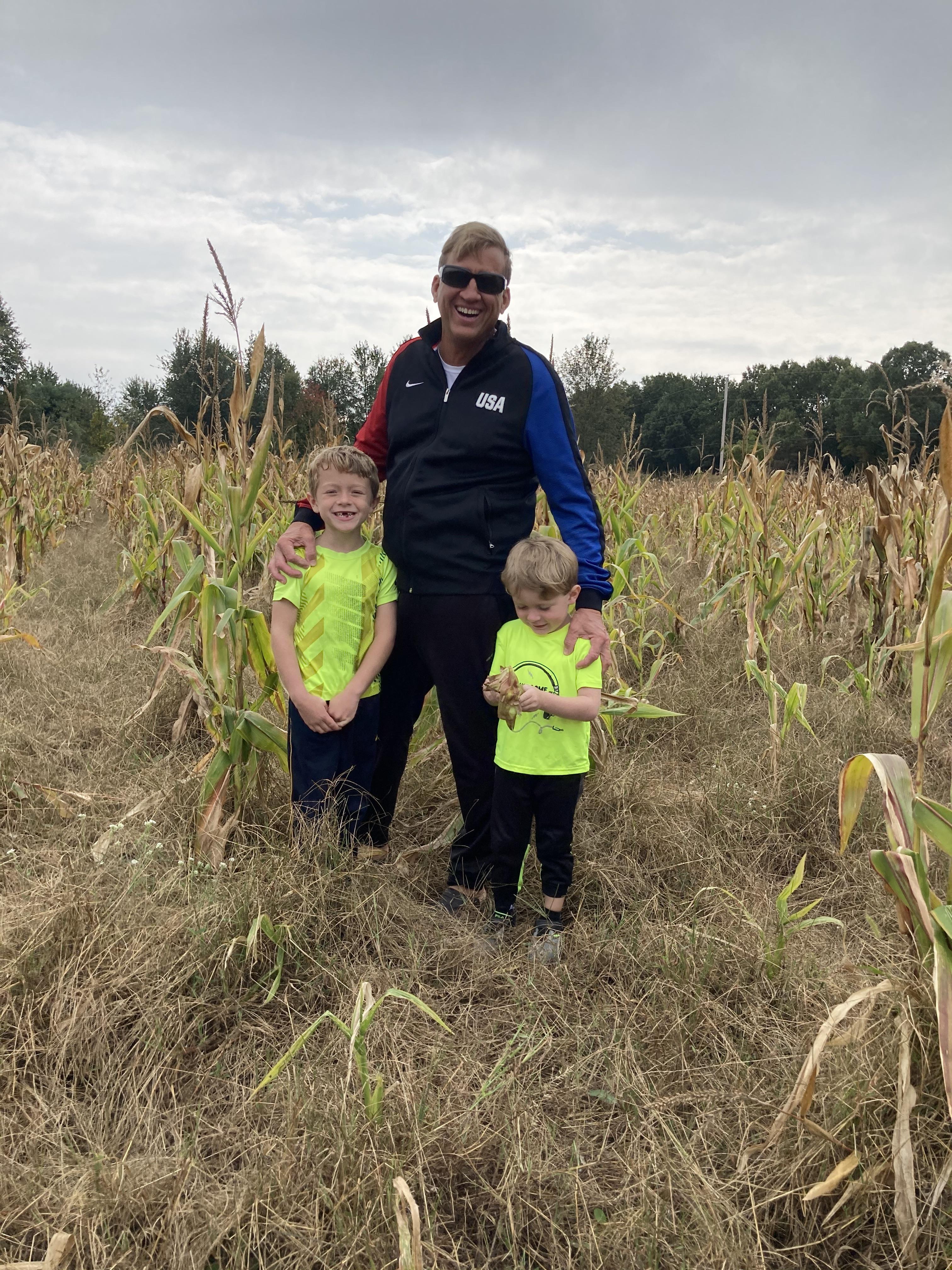 A man and two boys standing in a corn field