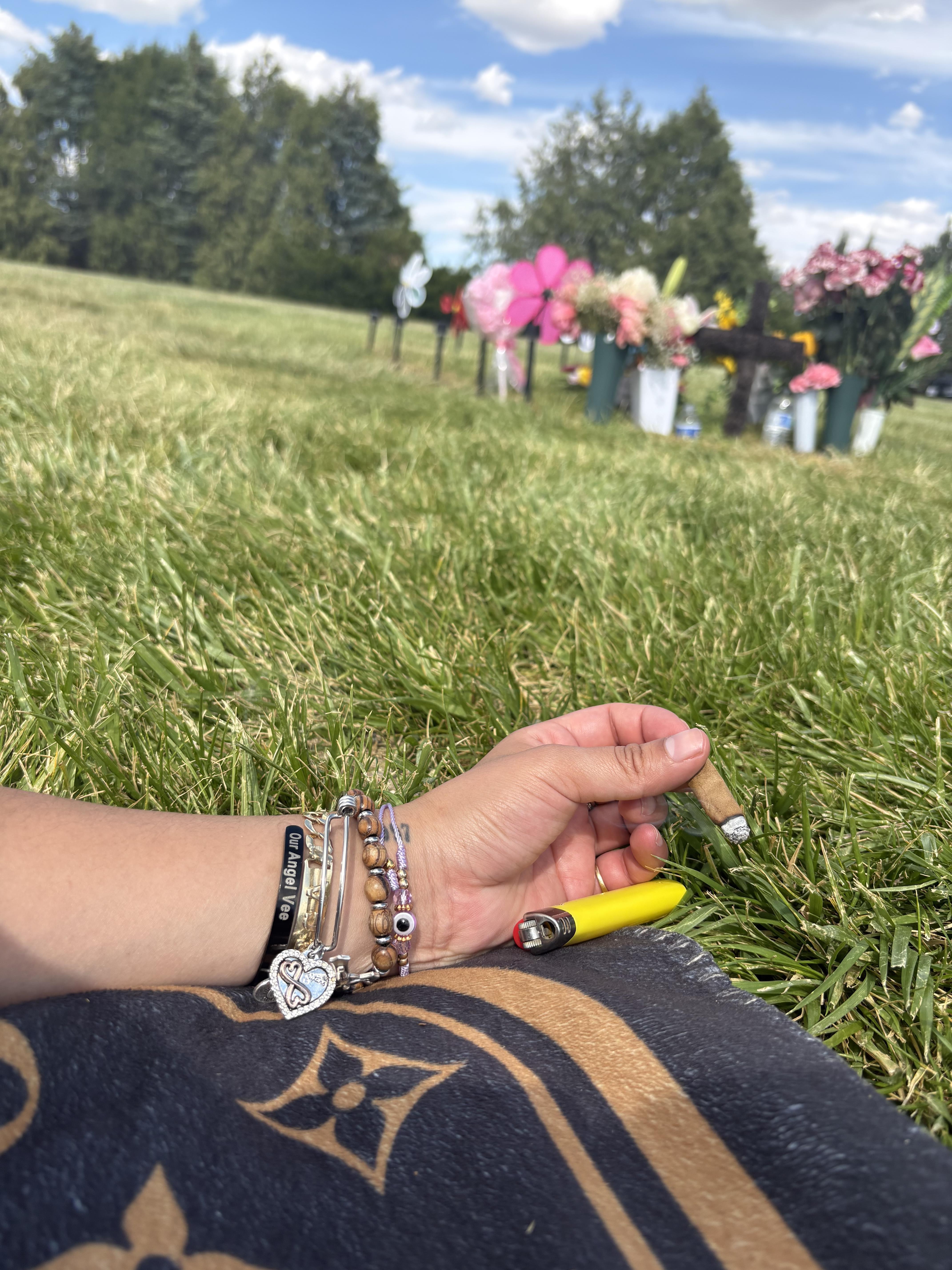 A person holding a cigarette in a grass field