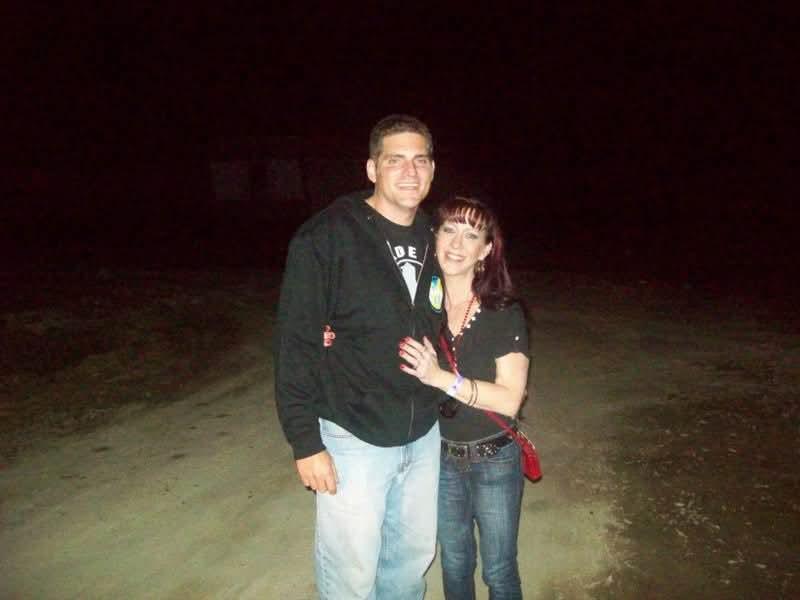 A man and woman standing on a dirt road at night